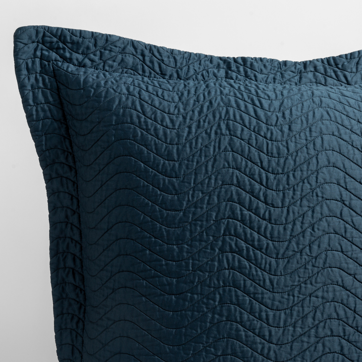 Midnight: a close up of a pillow corner showing the flange framing quilted cotton sateen shot against a white background. 