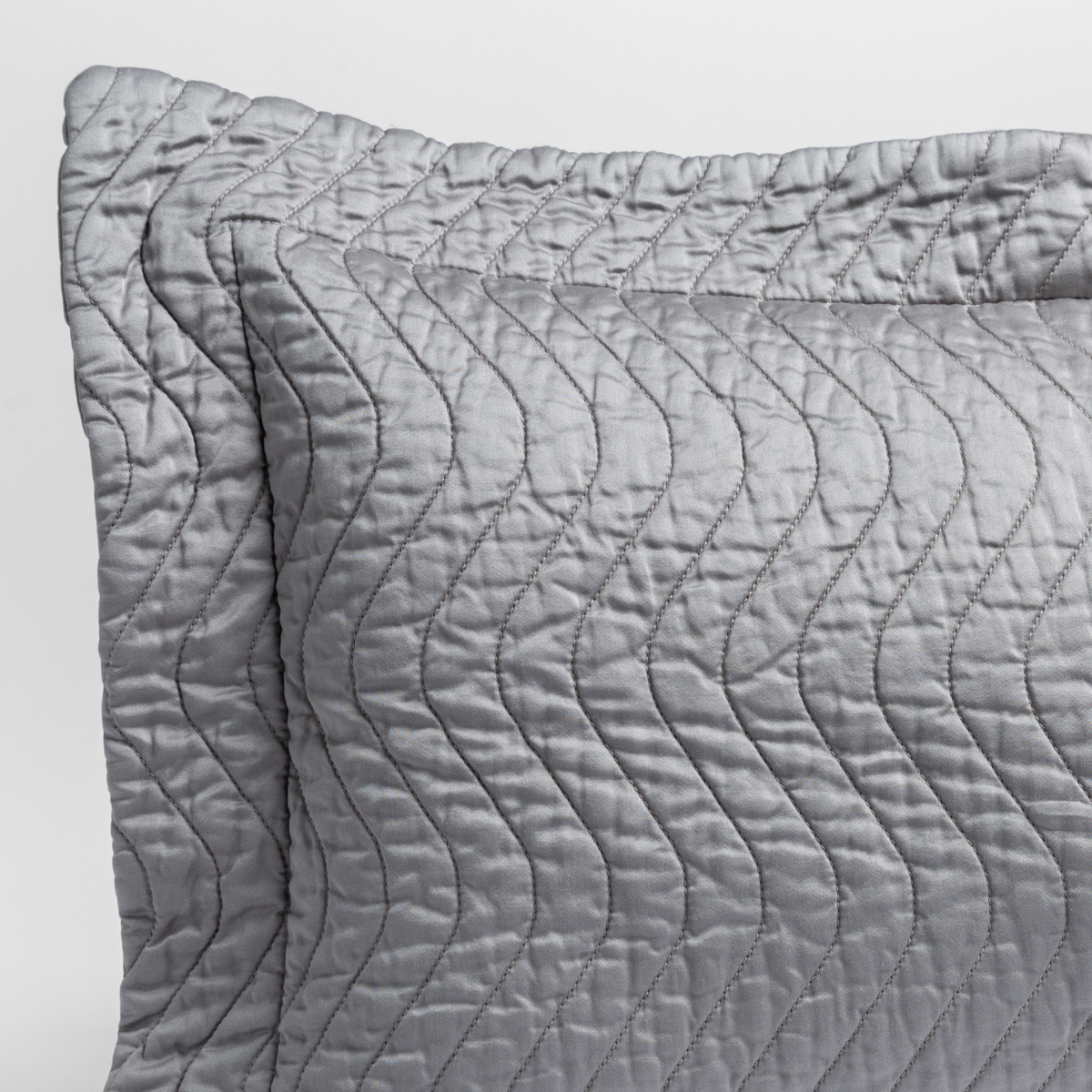 Moonlight: a close up of a pillow corner showing the flange framing quilted cotton sateen shot against a white background. 