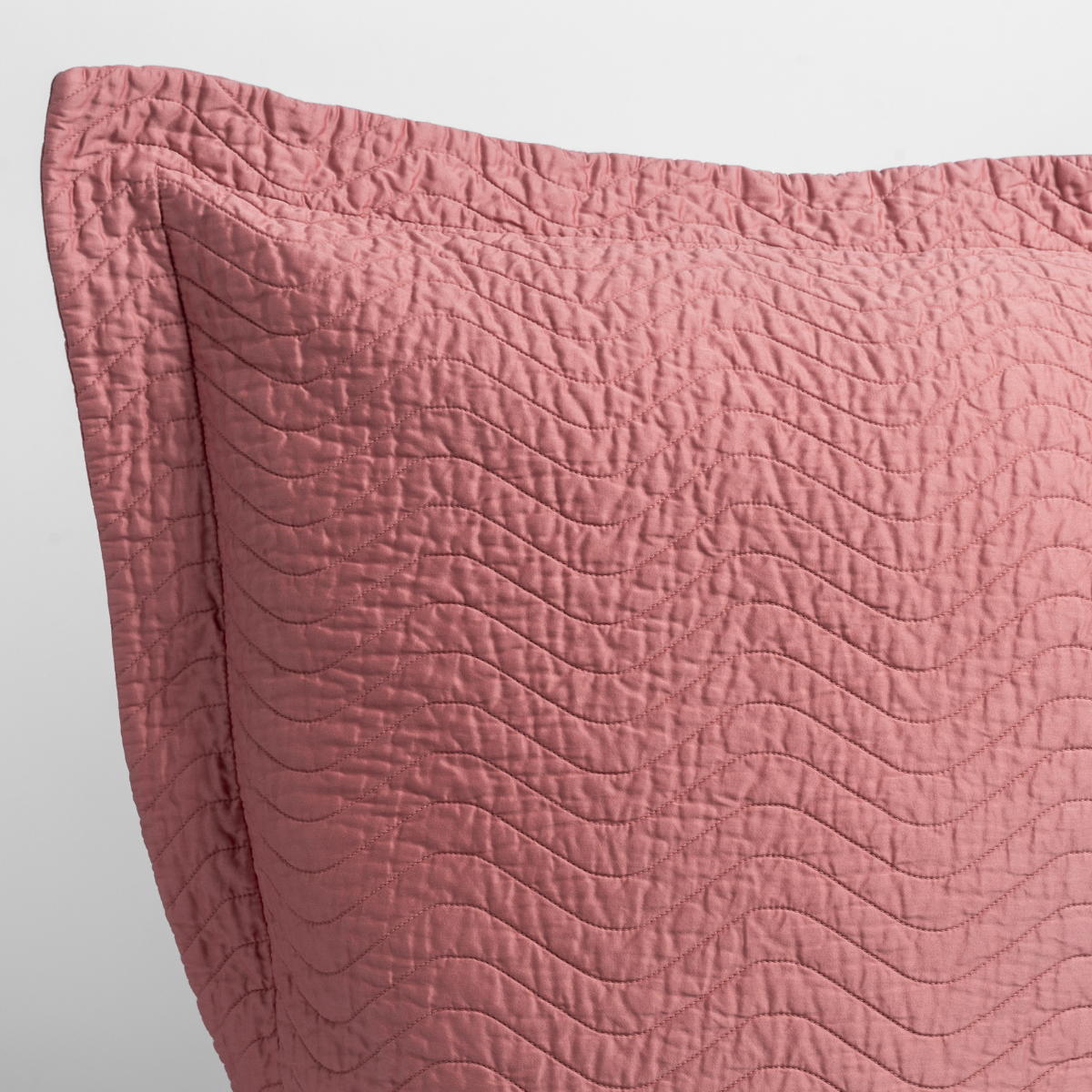 Poppy: a close up of a pillow corner showing the flange framing quilted cotton sateen shot against a white background. 