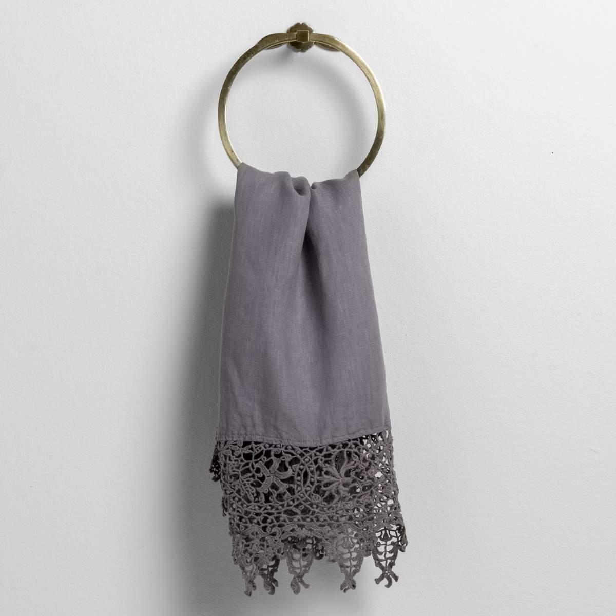 frida lace trimmed linen guest towel folded and hanging from a towel ring against a white background