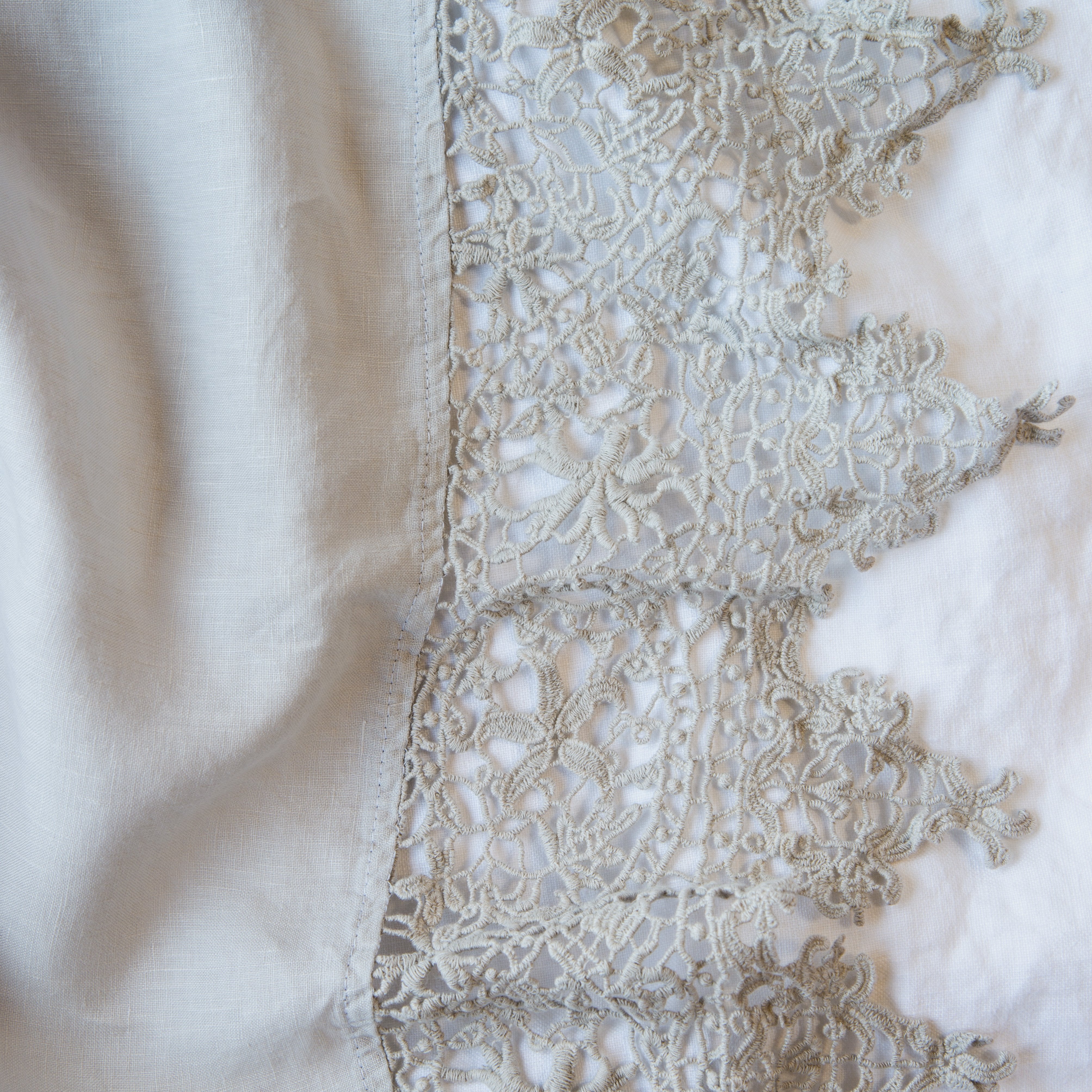 Sterling: A close up of Frida, an antique cotton lace trim on a linen body, shown in sterling, a silvery neutral light grey.