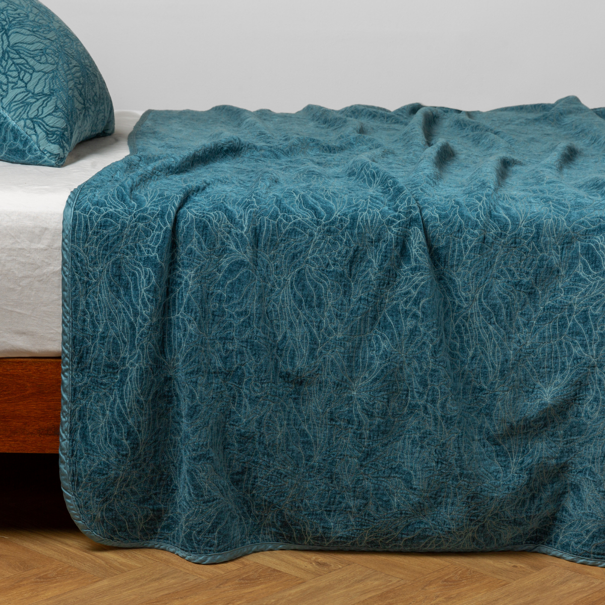 Cenote: side view of the chenille jacquard side of a bedspread with the cotton jacquard side showing on the matching sham — shown with a winter white fitted sheet. 