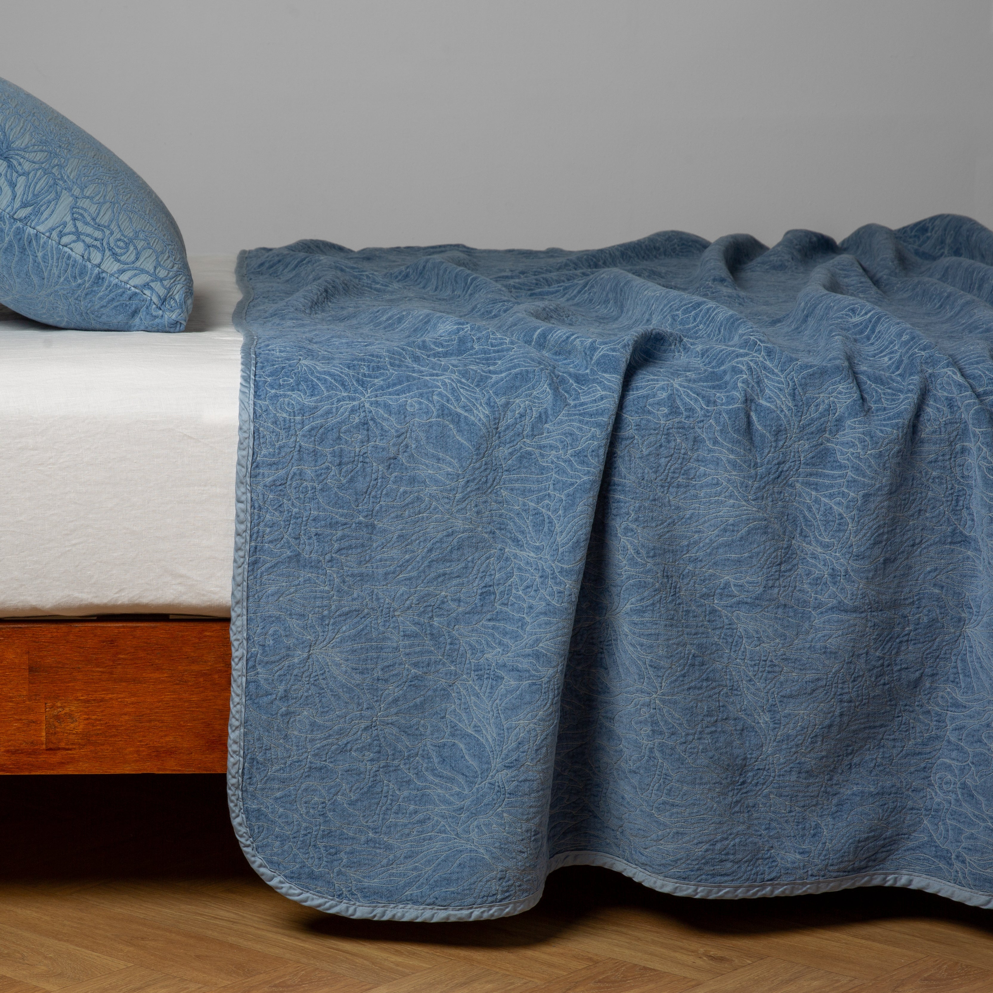 Tahoe Blue: side view of the chenille jacquard side of a bedspread with the cotton jacquard side showing on the matching sham — shown with a winter white fitted sheet. 