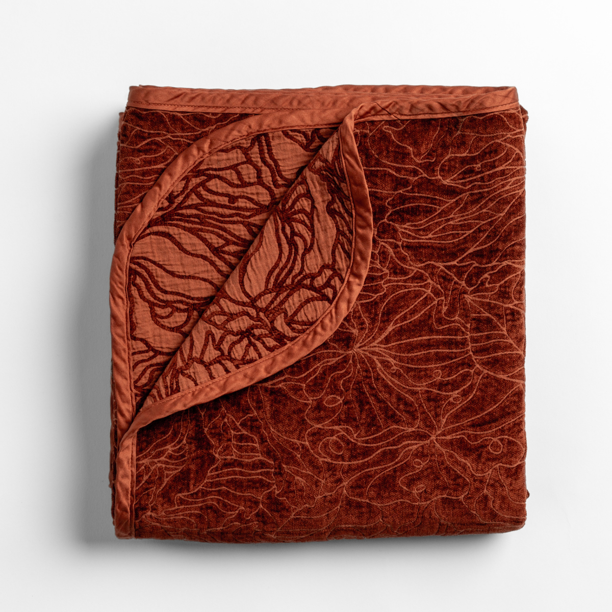 Autumn: A close-up of the corner of a folded Georgia Blanket in Autumn, a rich terracotta tone, shown against a white background. 