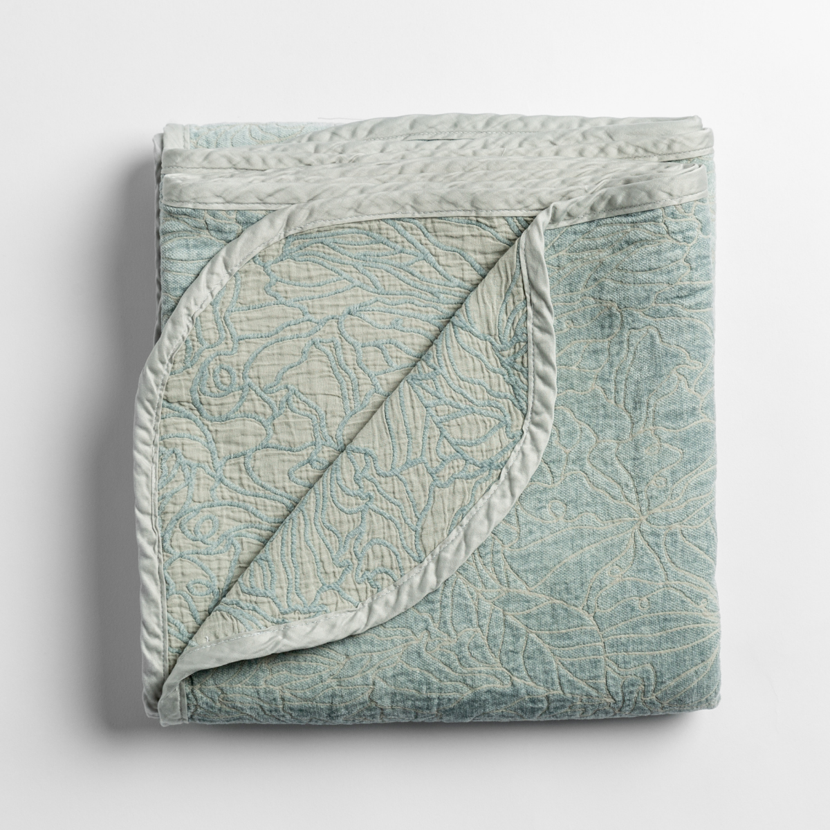  folded blanket with its cotton jacquard side visible on the corner foldback against the chenille jacquard side. 