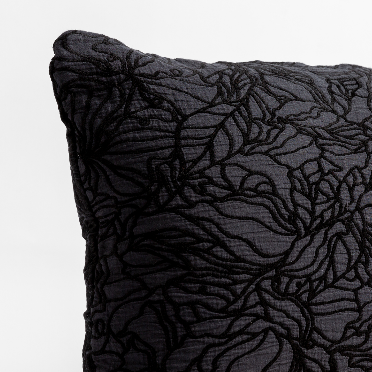 Corvino: close up of the cotton jacquard corner of a pillow cushion with a single-line floral pattern.