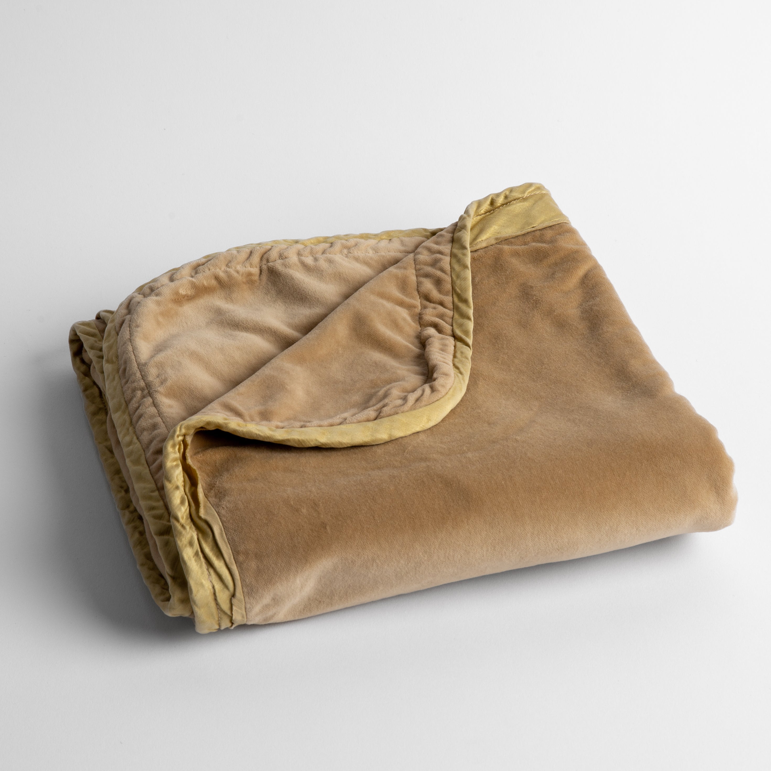 Honeycomb:  cotton velvet baby blanket trimmed with charmeuse, folded with a covern folded back to show trim contrast; shot overhead and at a slight angle against a white background. 