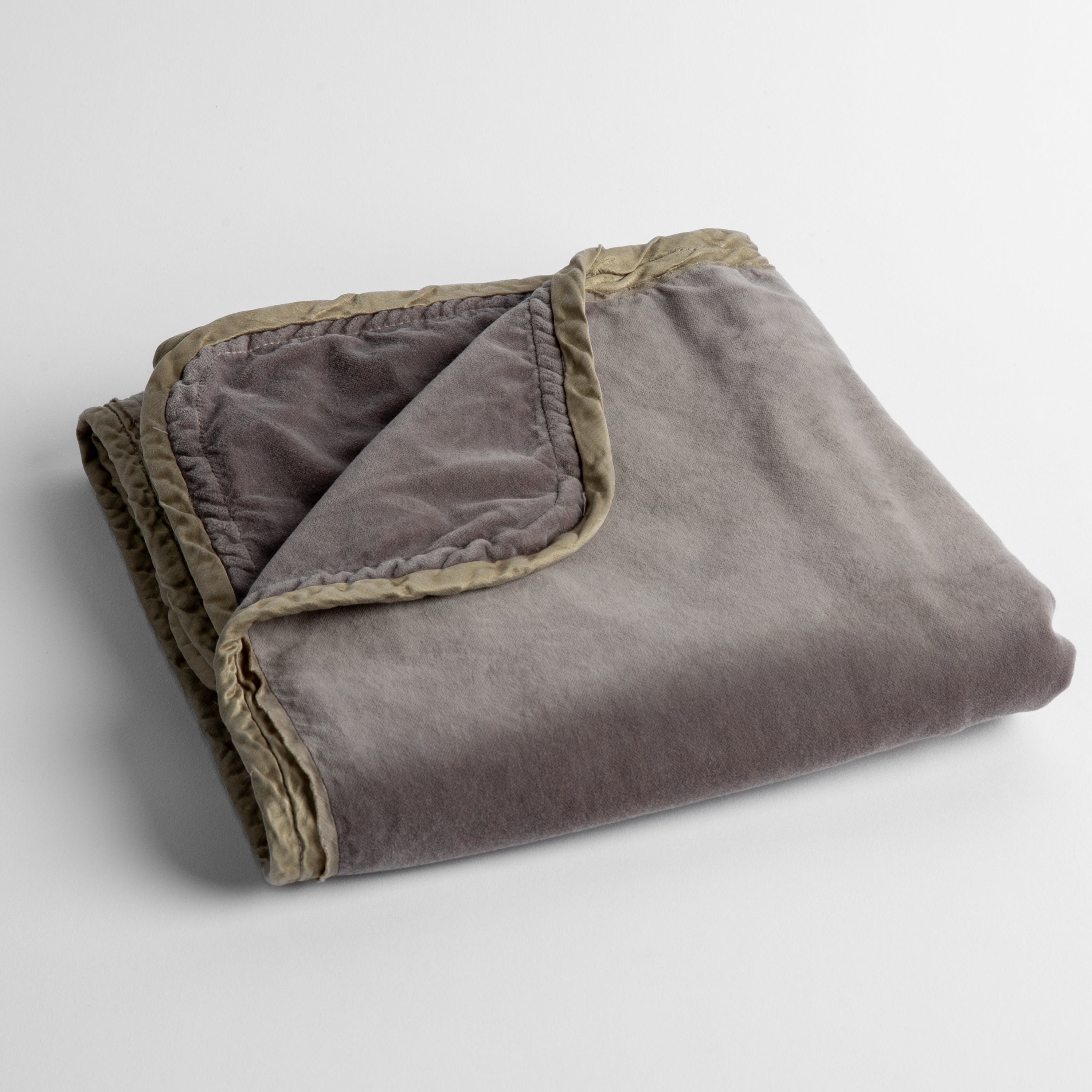 Moonlight: cotton velvet baby blanket trimmed with charmeuse, folded with a covern folded back to show trim contrast; shot overhead and at a slight angle against a white background. 