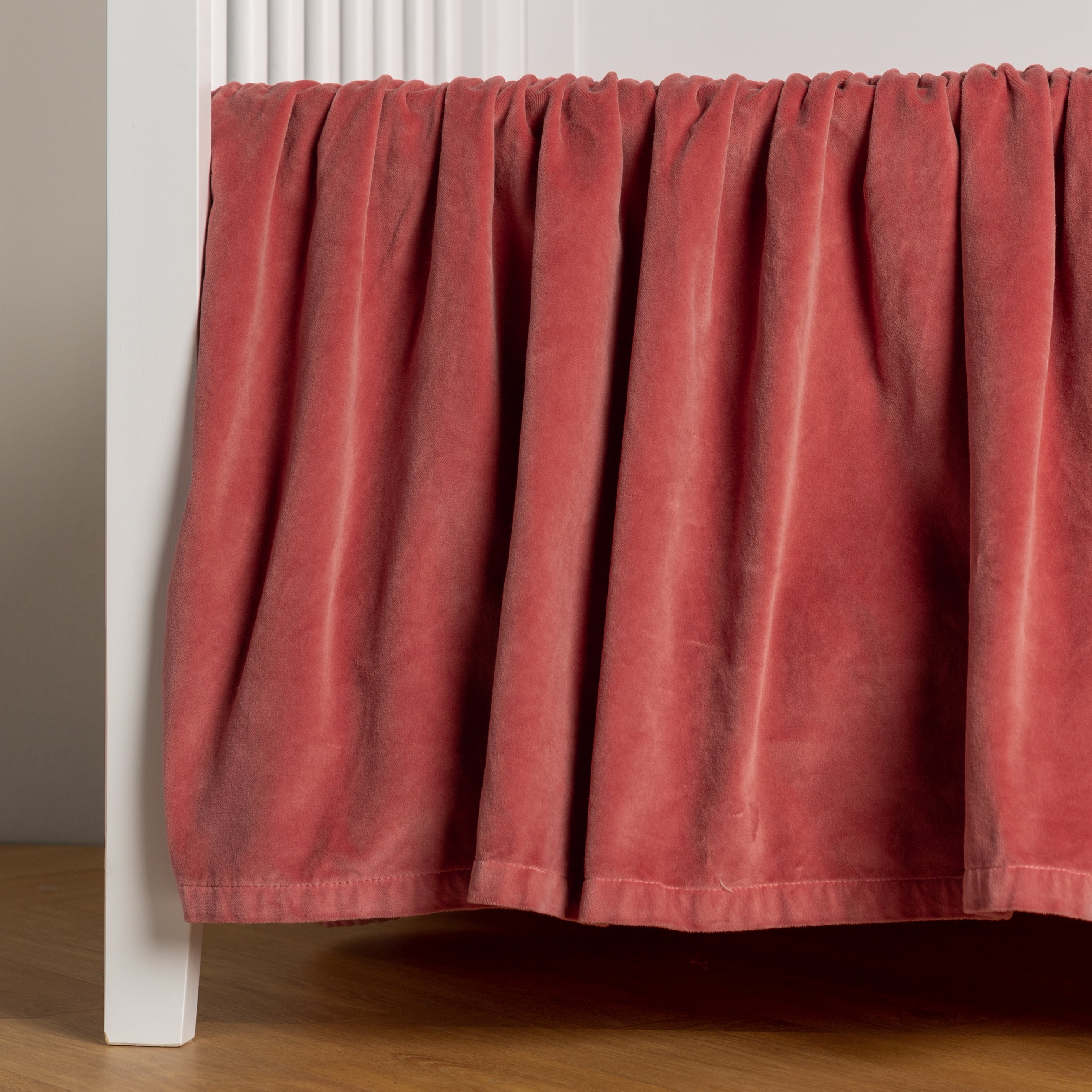 Poppy:  cotton velvet crib skirt shown on a white crib . 