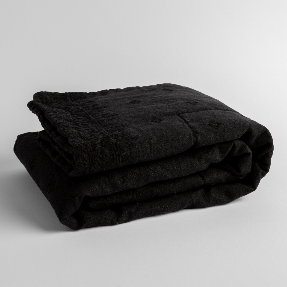 Corvino:  embroidered linen baby blanket folded and shown  overhead from a slight angle against a white background. 