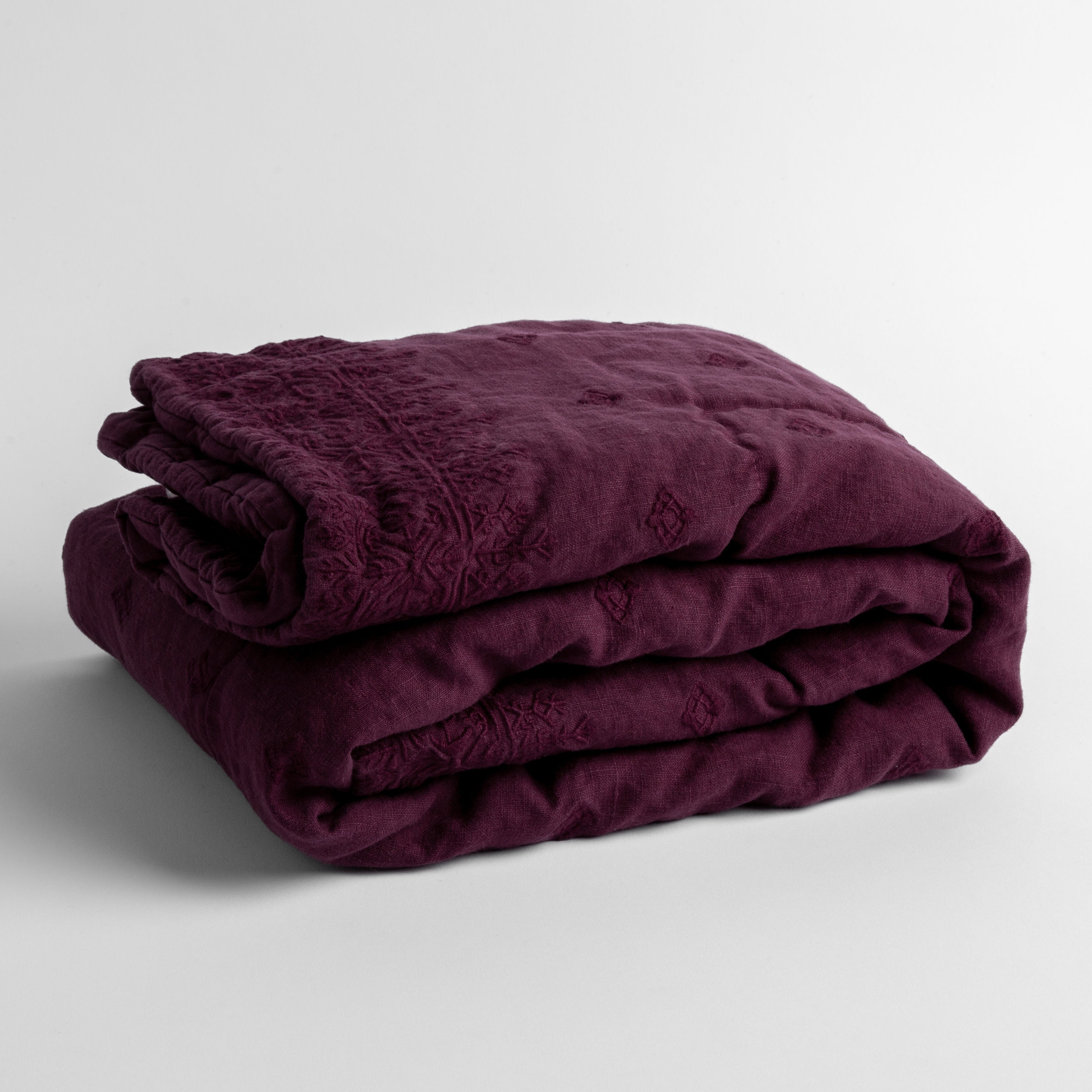 Fig:  embroidered linen baby blanket folded and shown  overhead from a slight angle against a white background. 