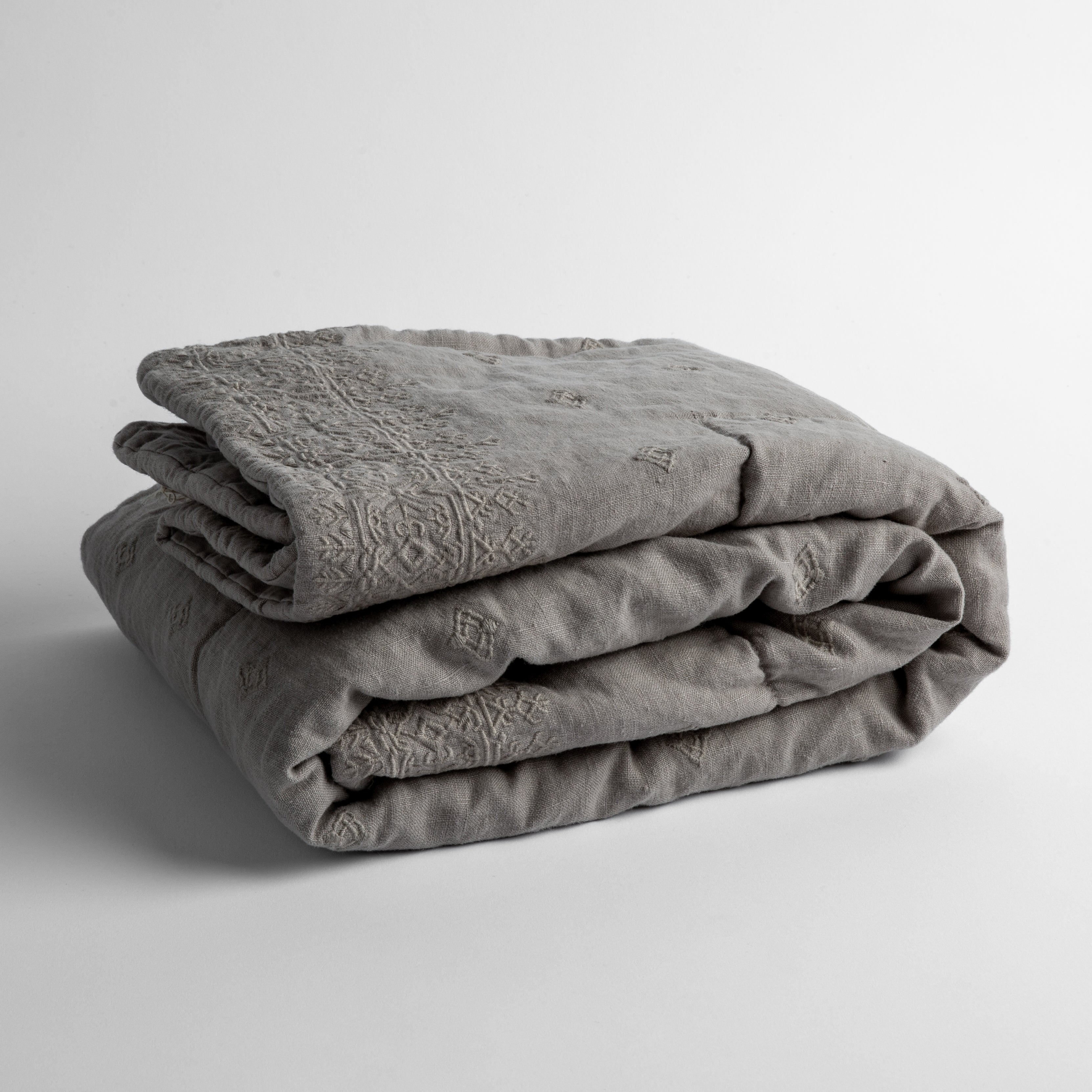 Fog:  embroidered linen baby blanket folded and shown  overhead from a slight angle against a white background. 