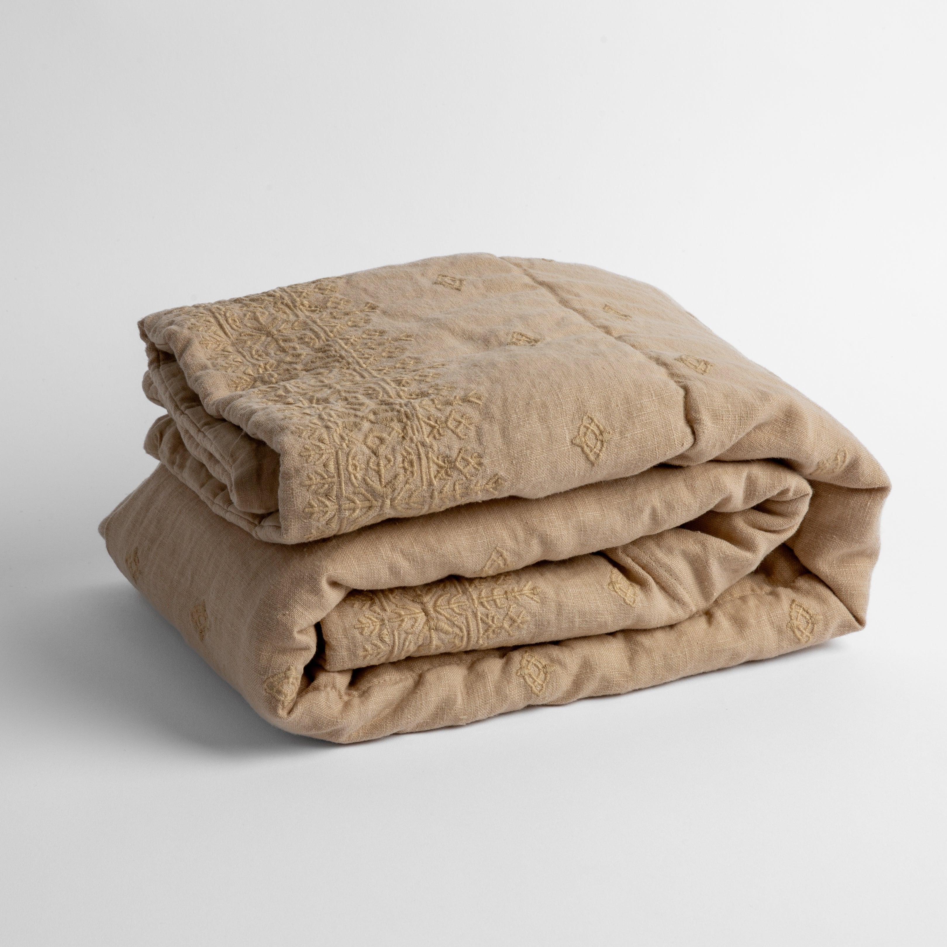 Honeycomb: embroidered linen baby blanket folded and shown  overhead from a slight angle against a white background. 