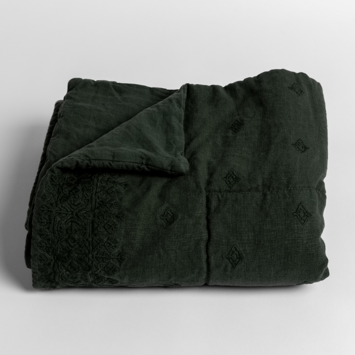 Juniper: embroidered midweight linen baby blanket folded with the corner folded back to reveal its unembroidered linen back. 