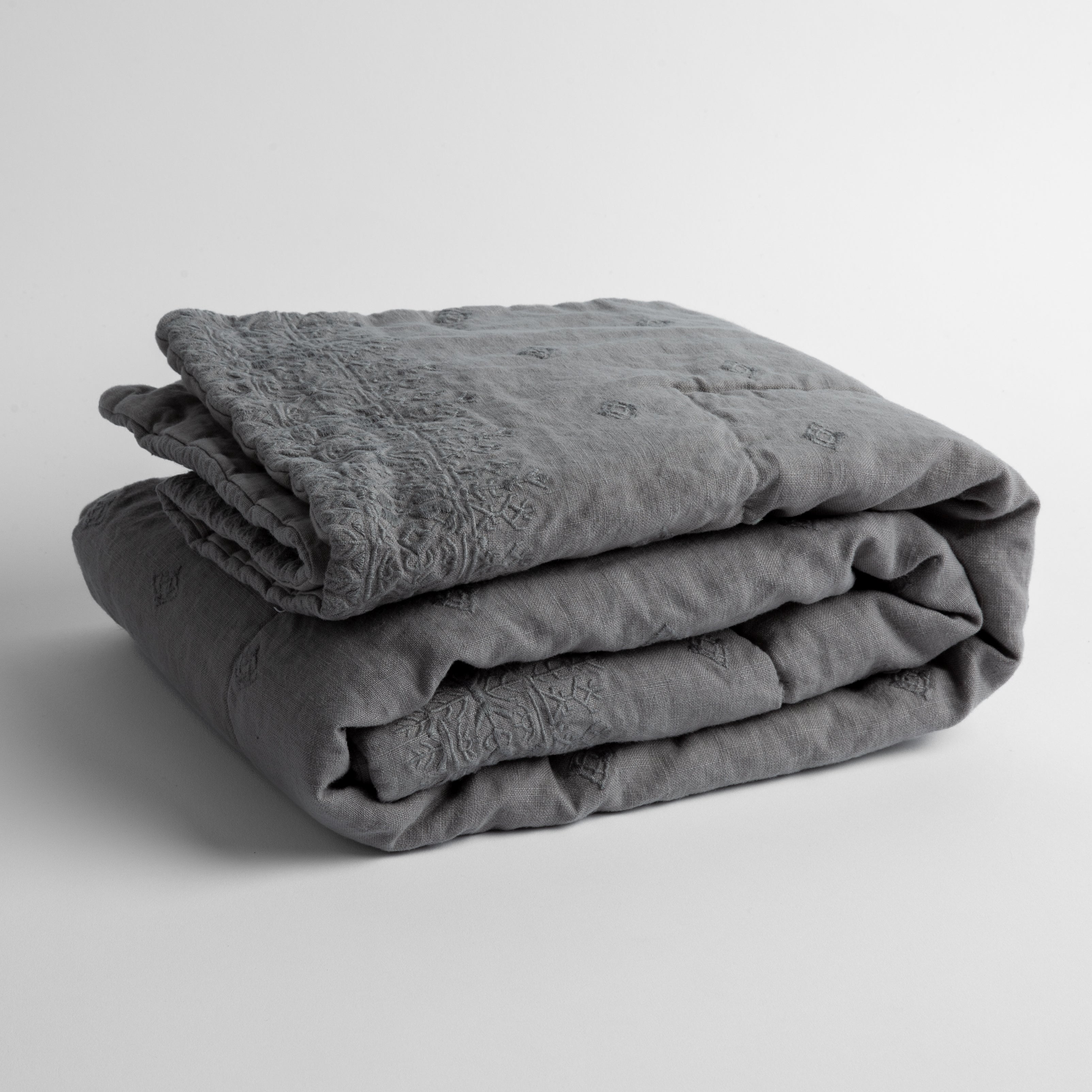 Moonlight:  embroidered linen baby blanket folded and shown  overhead from a slight angle against a white background. 