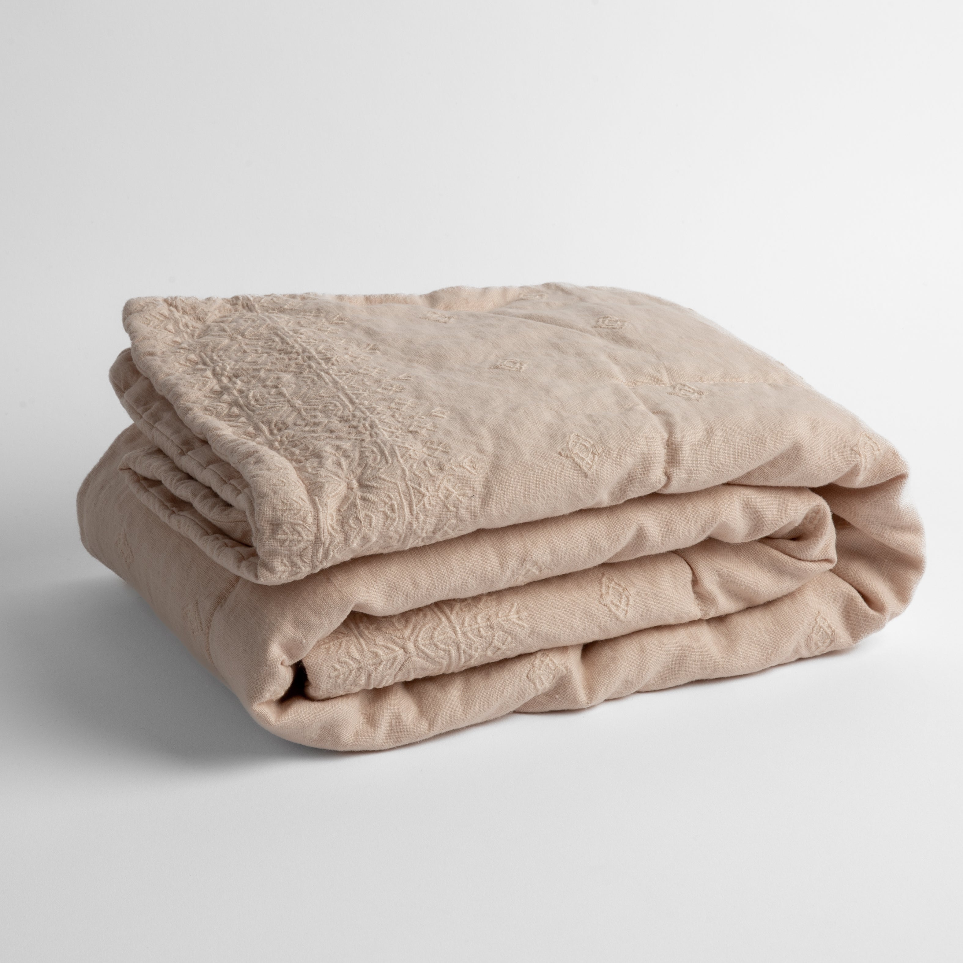 Pearl: embroidered linen baby blanket folded and shown  overhead from a slight angle against a white background. 