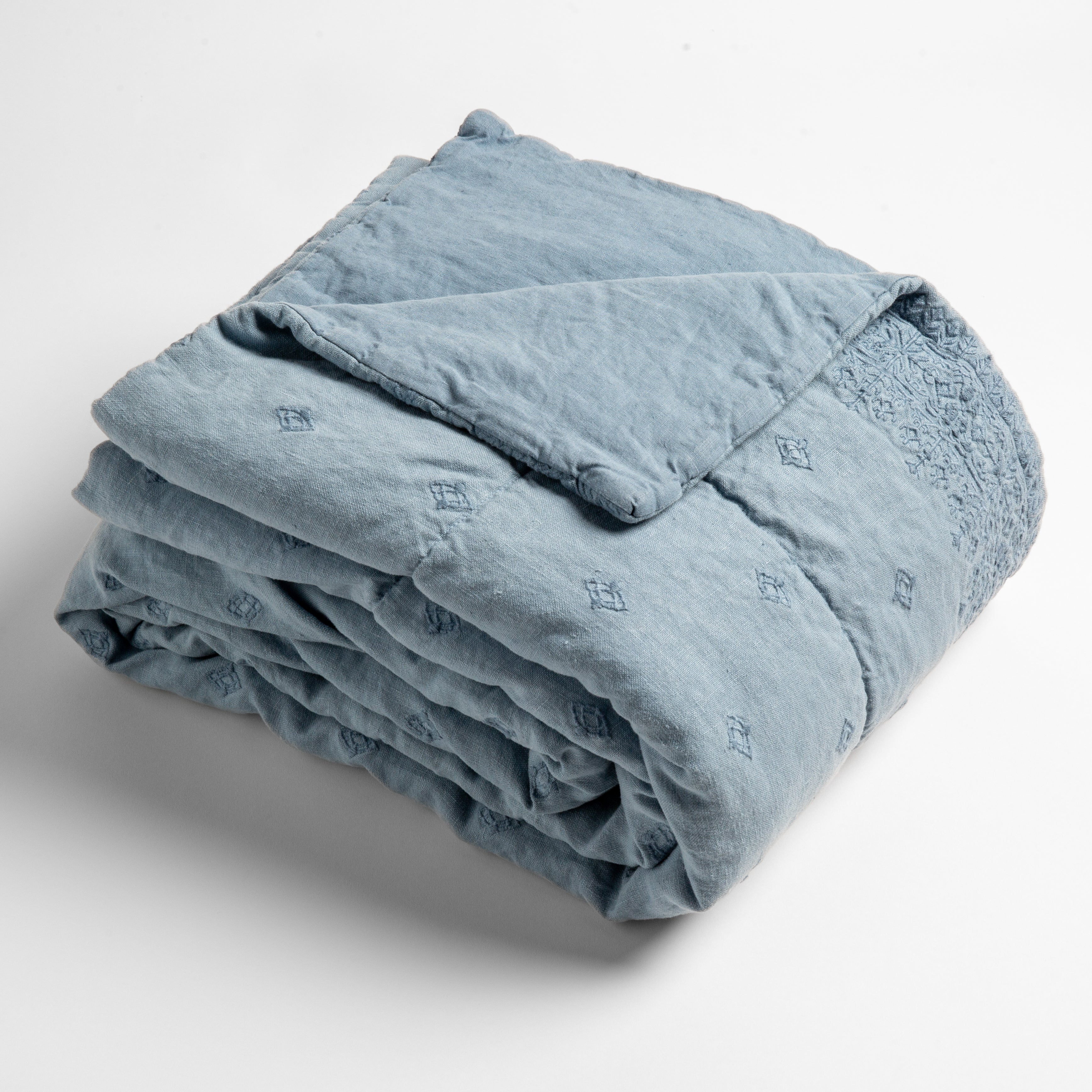 Tahoe Blue:  embroidered linen baby blanket folded and shown  overhead from a slight angle against a white background. 