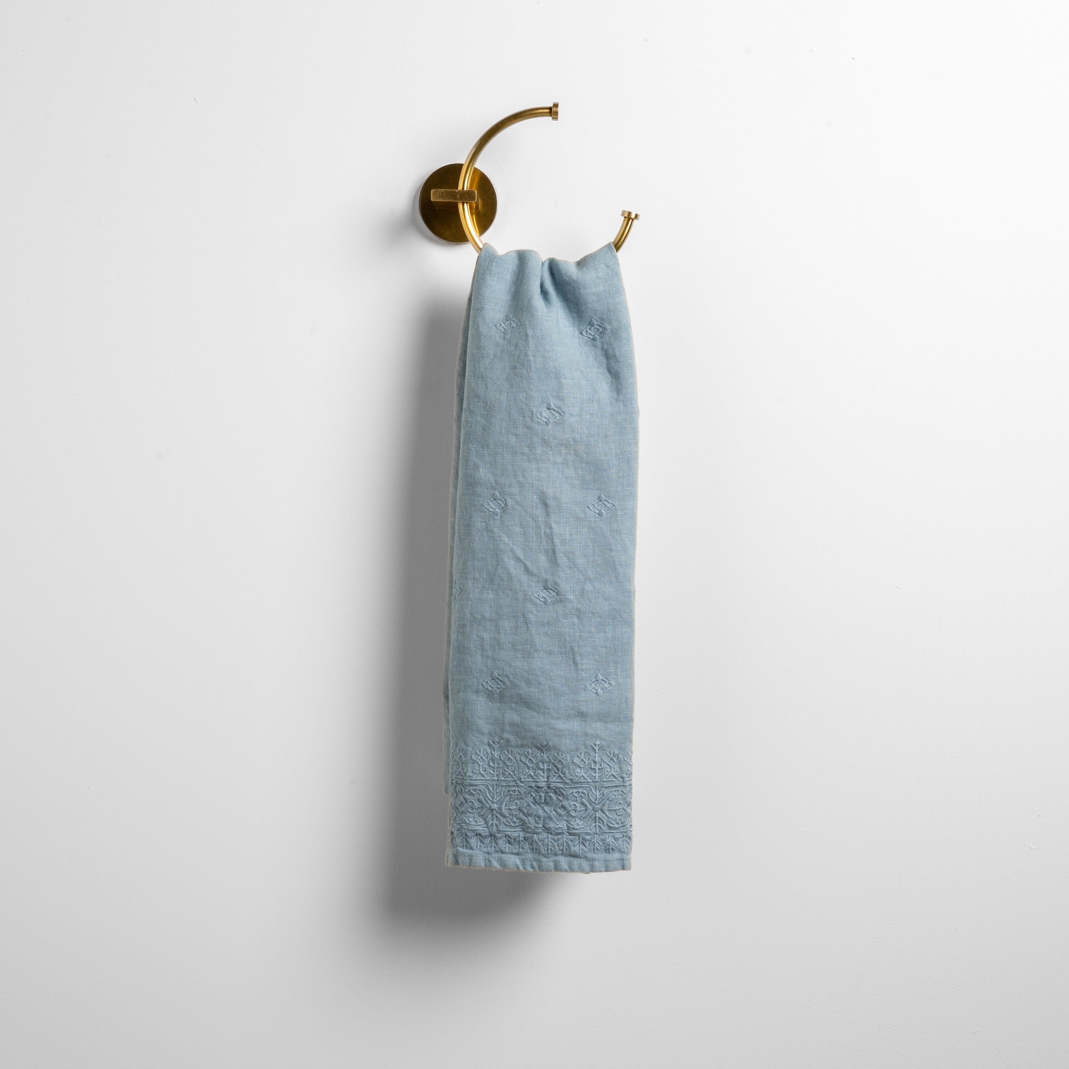 Tahoe Blue: guest towel draped through a decorative brass towel ring against a white background.
