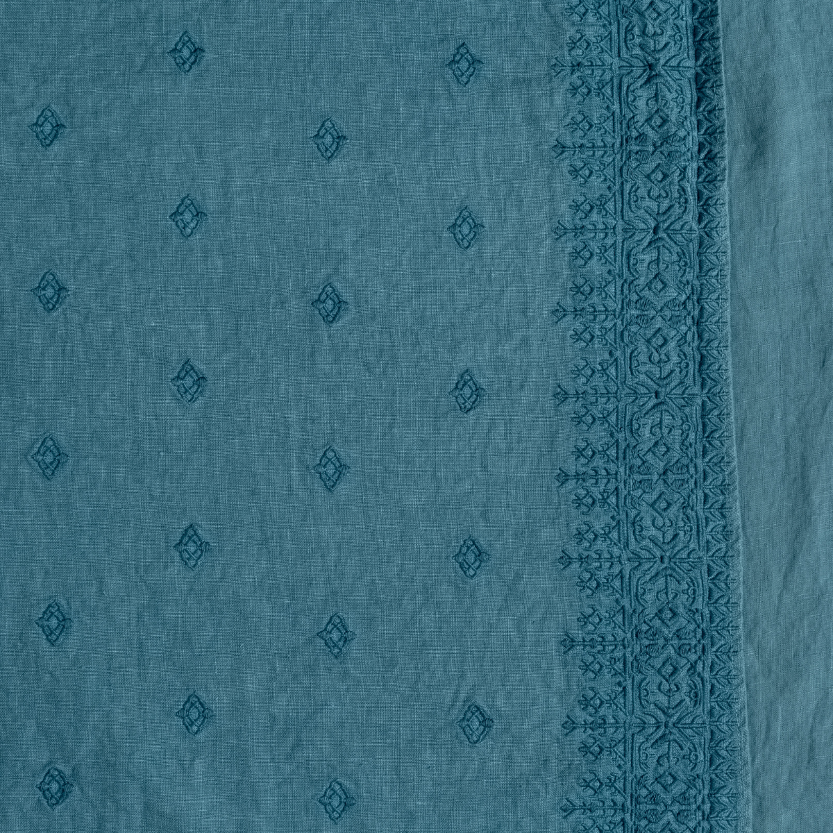 Cenote: A close up of embroidered midweight linen fabric in cenote, a vibrant, ocean-inspired blue-green.