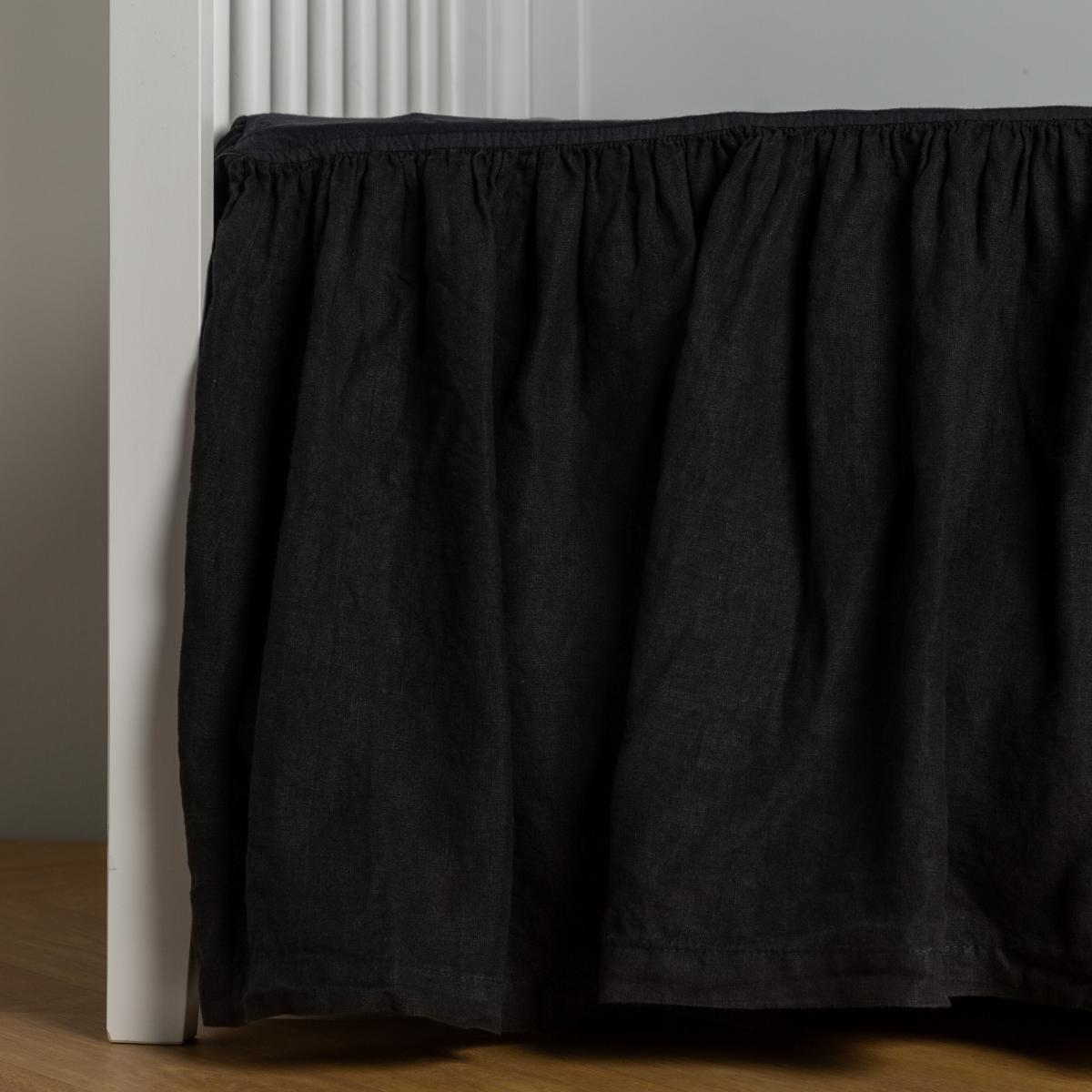 Corvino:  crib skirt shown on a white crib with no mattress against a white wall and medium wood flooring. 