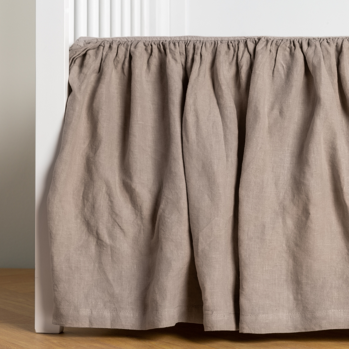 Fog:  crib skirt shown on a white crib with no mattress against a white wall and medium wood flooring. 