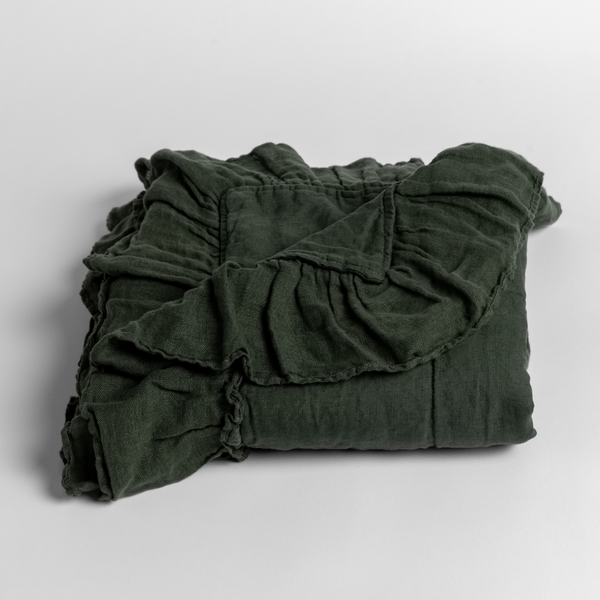 Juniper: folded baby blanket with a corner pulled back to show the ruffle trim against a white background. 