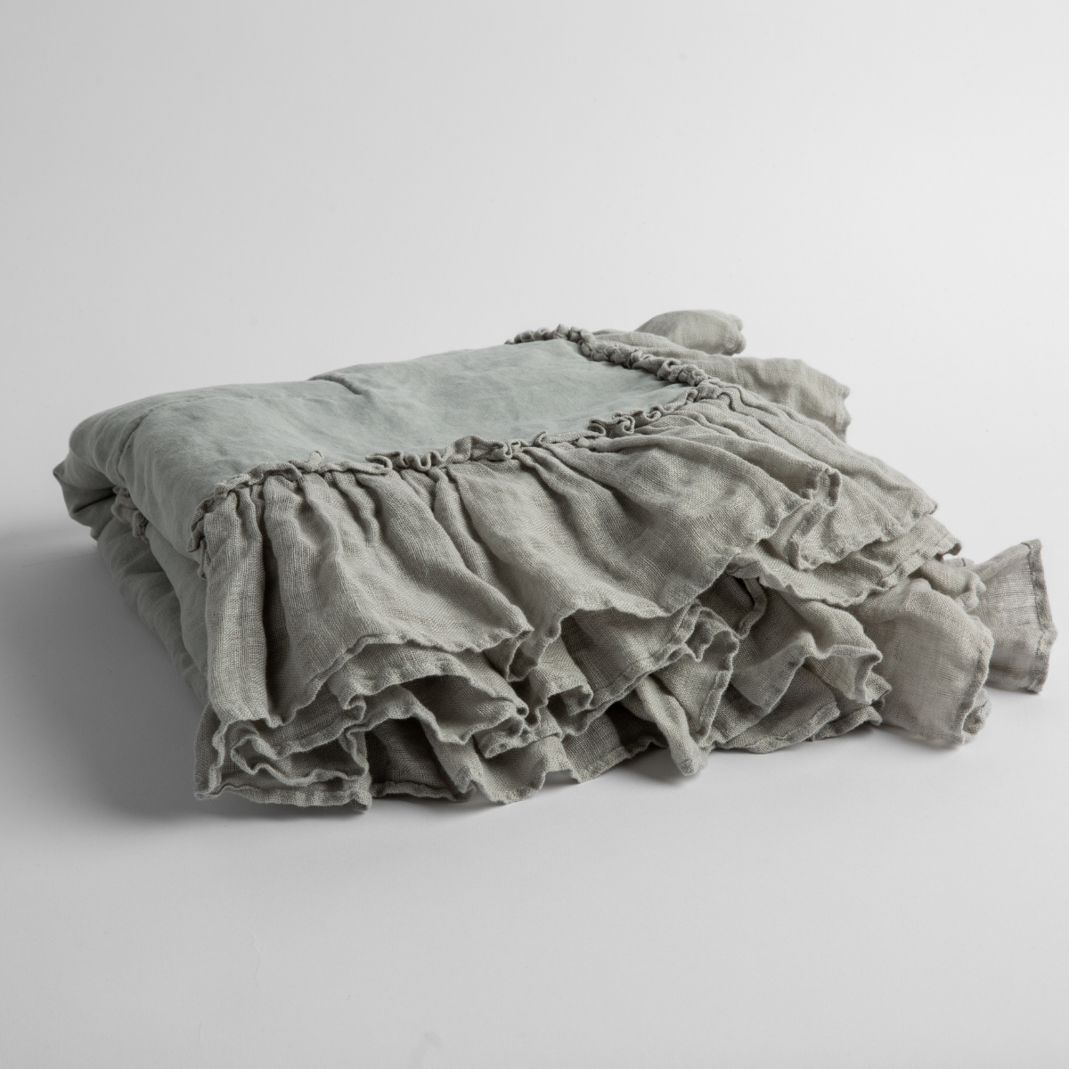 Mineral:  a folded linen with linen whisper ruffled blanket folded and positioned to show the ruffle detail against a white background and slightly overhead. 