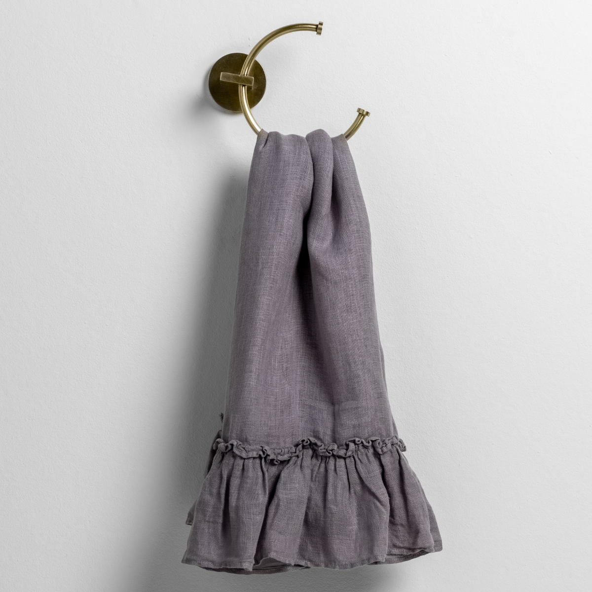 linen whisper guest towel folded and draped through a towel hook against a white background. 