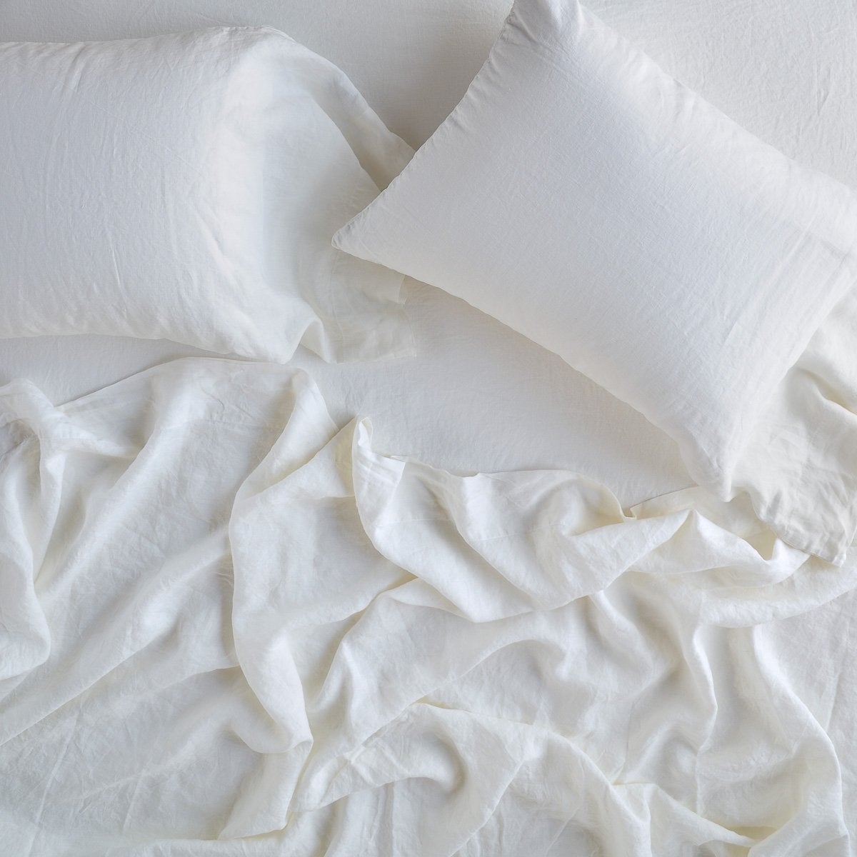 Winter White: sleeping pillows laid flat on rumpled matching sheeting - overhead view.