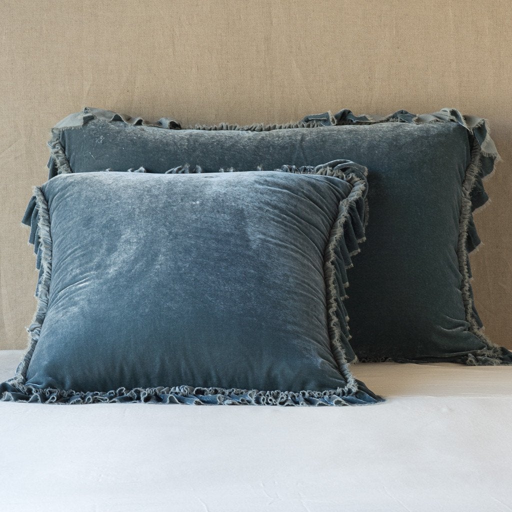 Mineral: shams leaning upright on white sheets against a neutral headboard.