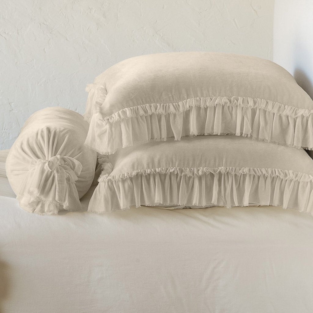 Parchment: Two shams stacked flat next to matching bolster. Close-up side view highlights the ruffle trim.