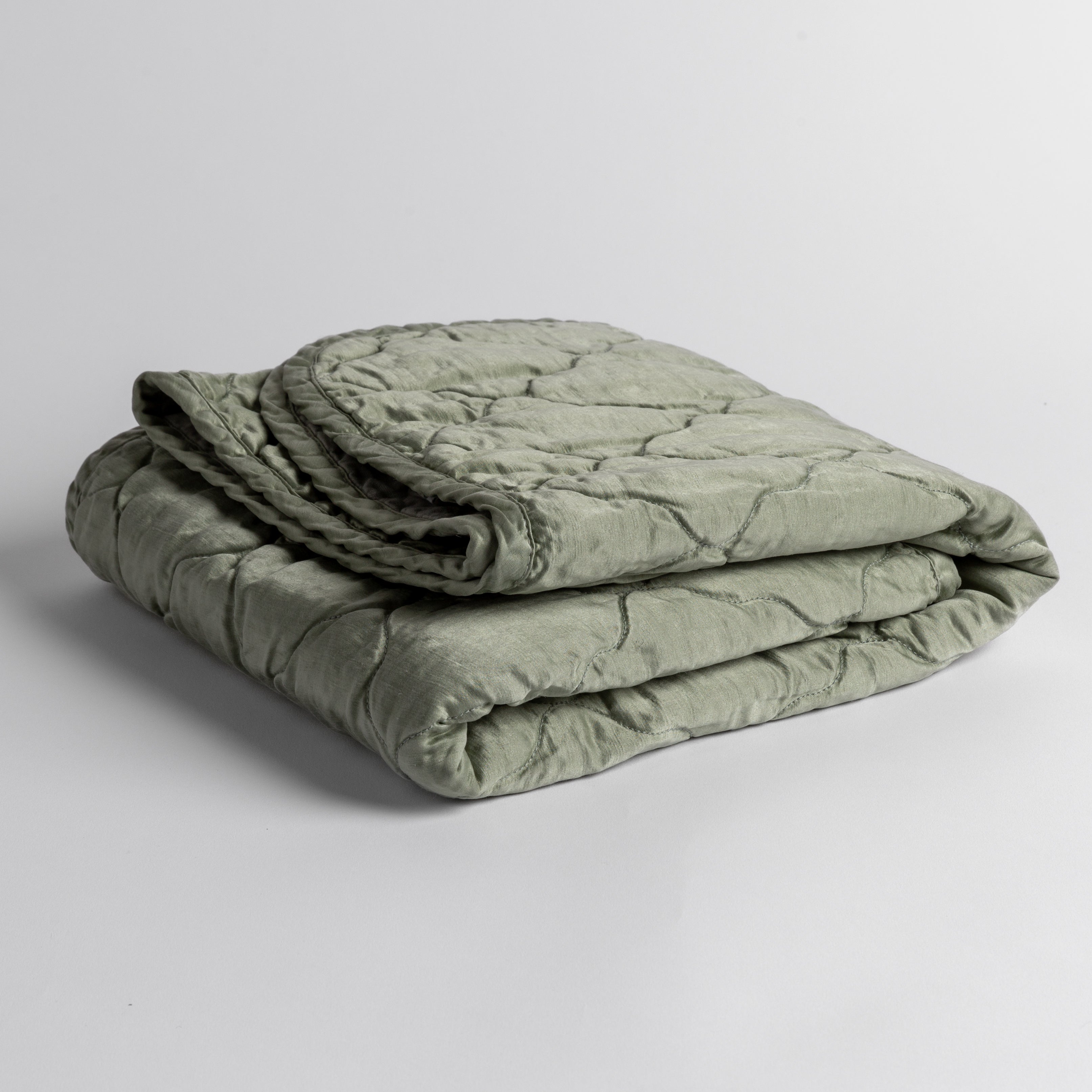 Eucalyptus:  quilted charmeuse blanket folded and shown against a white background from a slight overhead angle. 