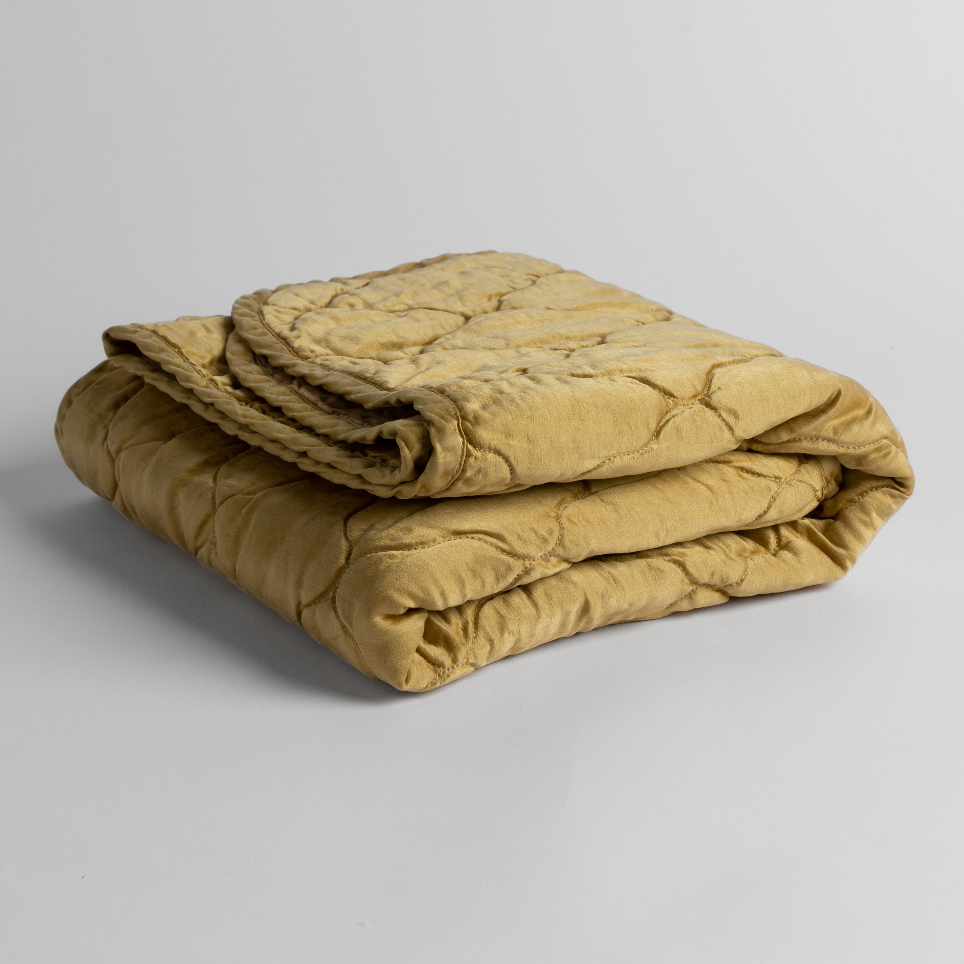 Honeycomb:  quilted charmeuse blanket folded and shown against a white background from a slight overhead angle. 