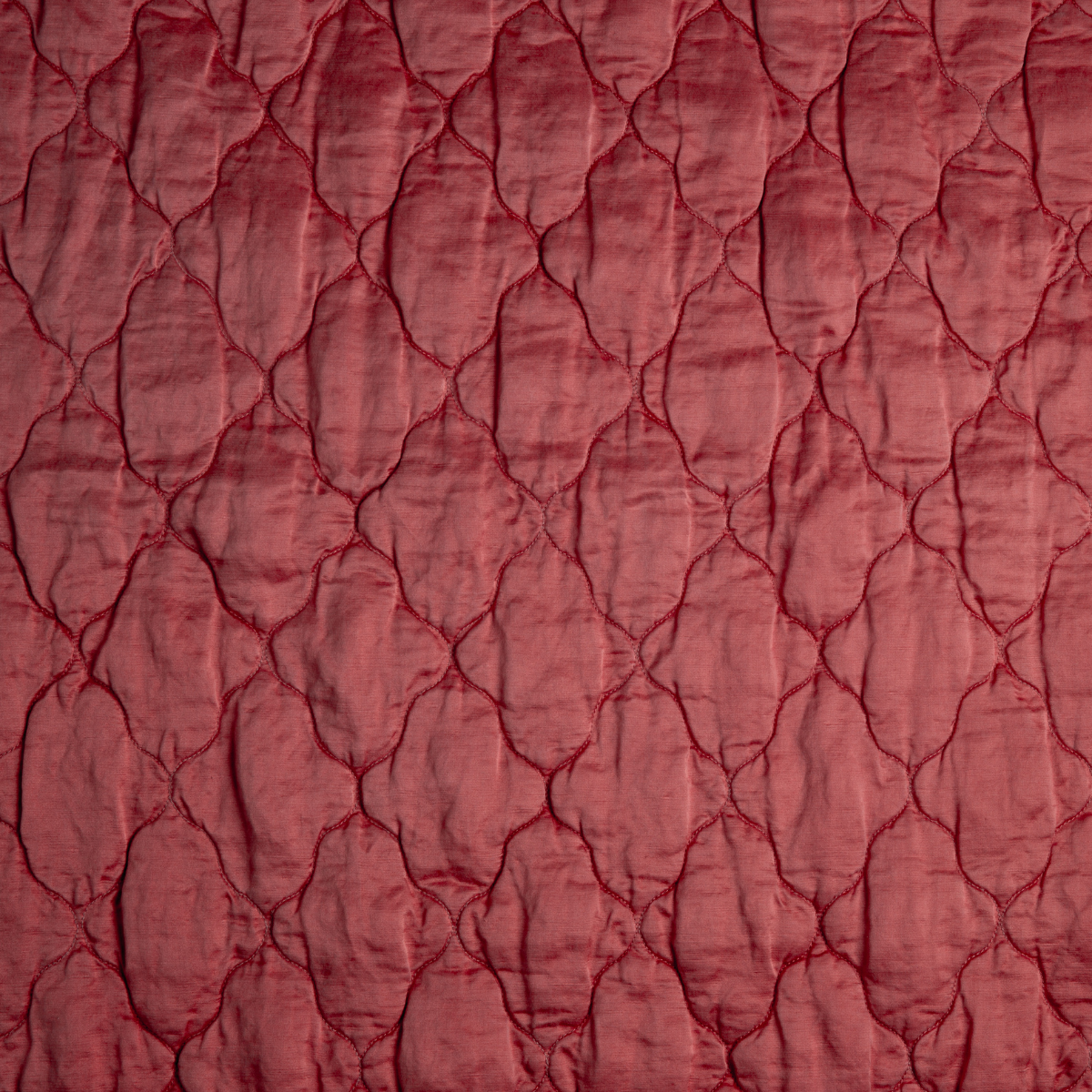 Poppy: A close up of quilted charmeuse fabric in poppy, a warm coral pink.