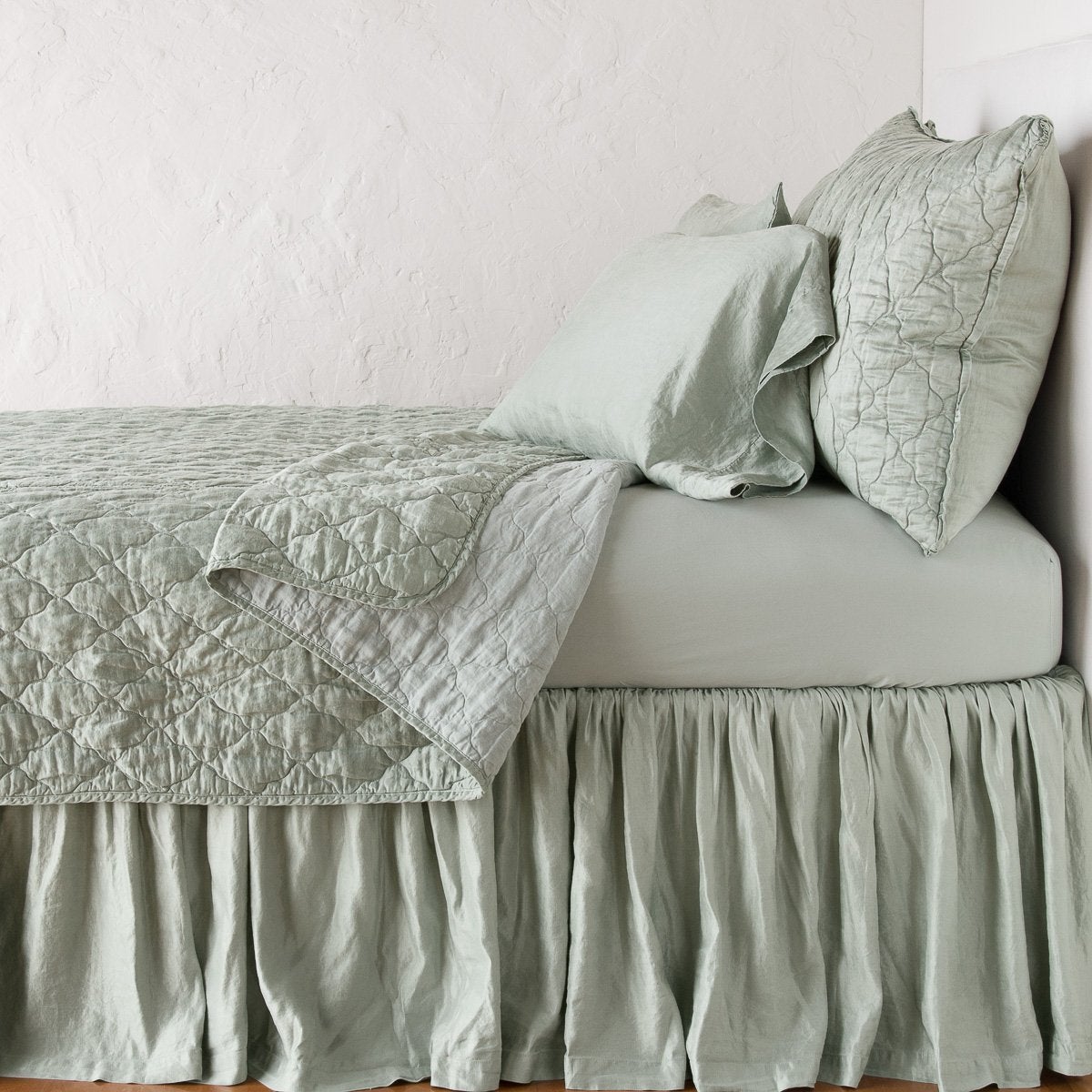Eucalyptus: coverlet neatly folded back to reveal linen reverse, on a monochromatic bed - side view.