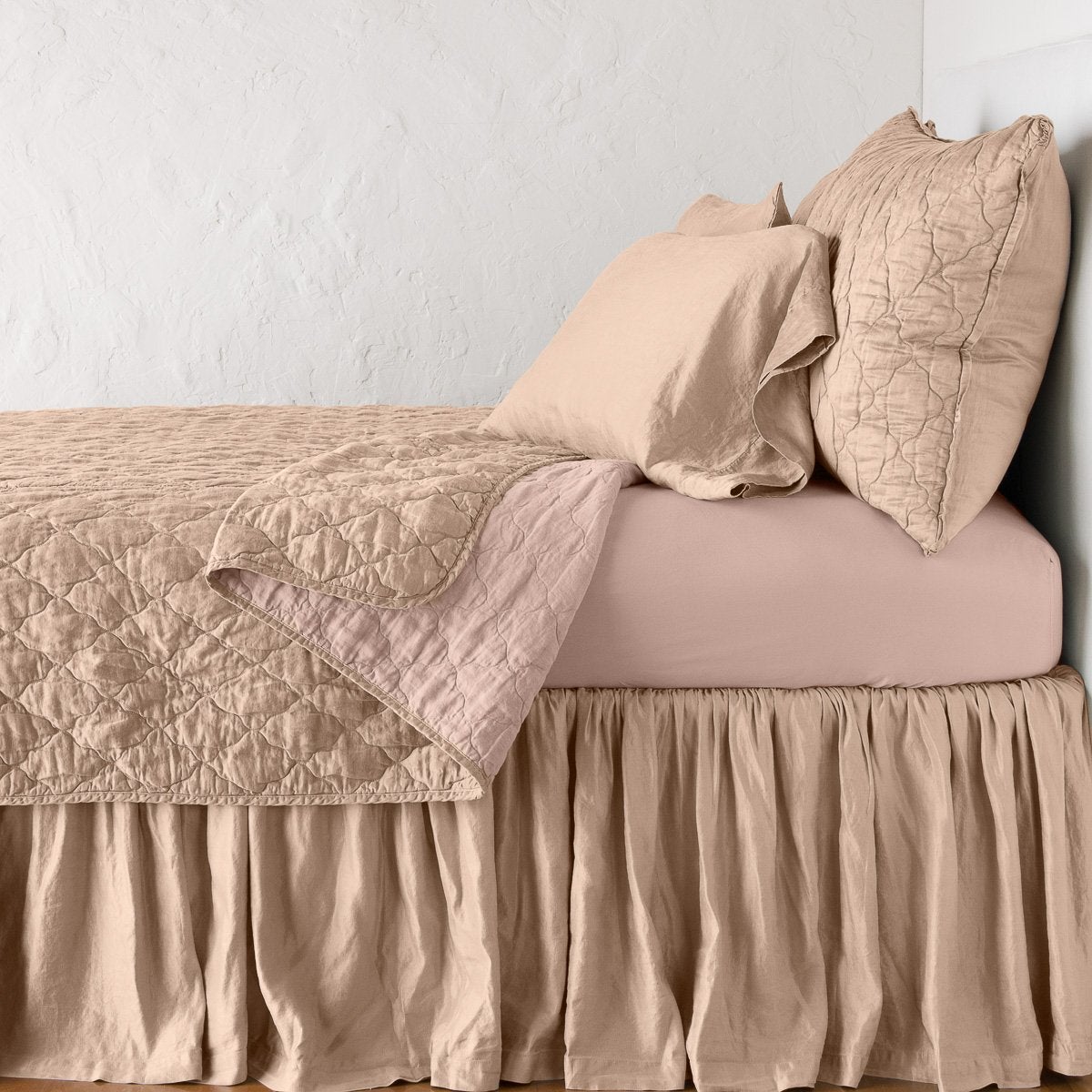 Rouge: coverlet neatly folded back to reveal linen reverse, on a monochromatic bed - side view.