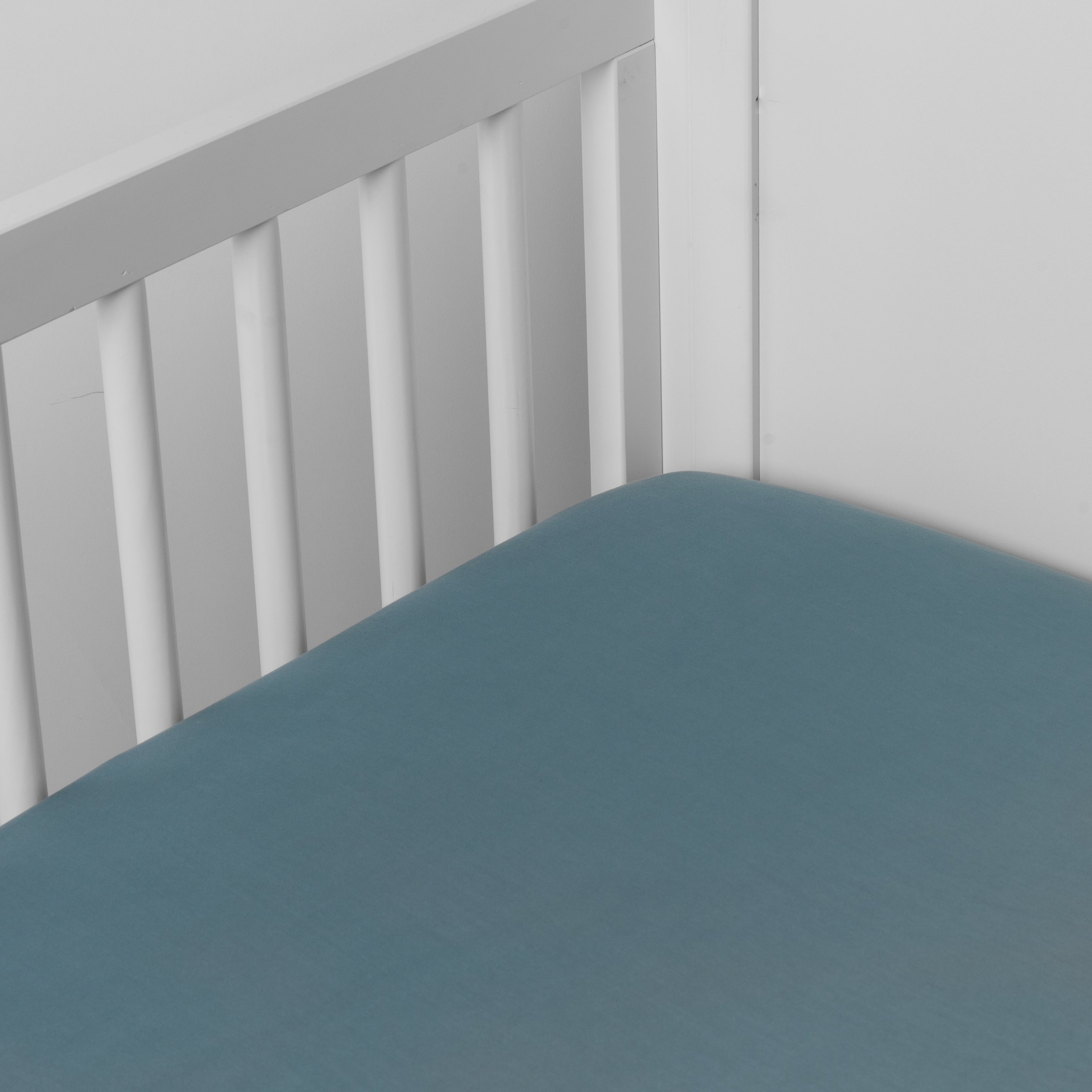 Cenote:  crib sheet shown on a mattress shown from overhead into the corner of a crib. 