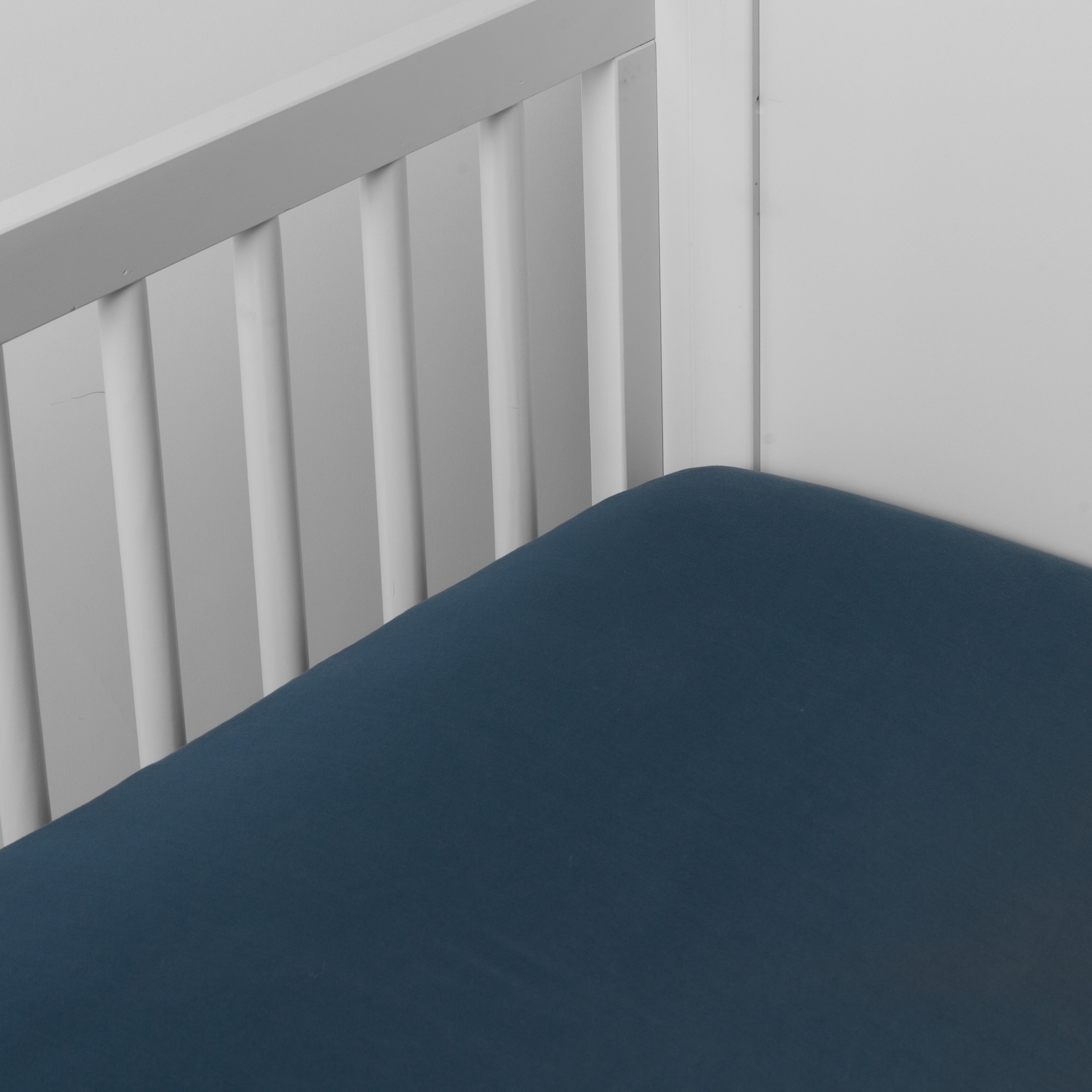 Midnight:  crib sheet shown on a mattress shown from overhead into the corner of a crib. 