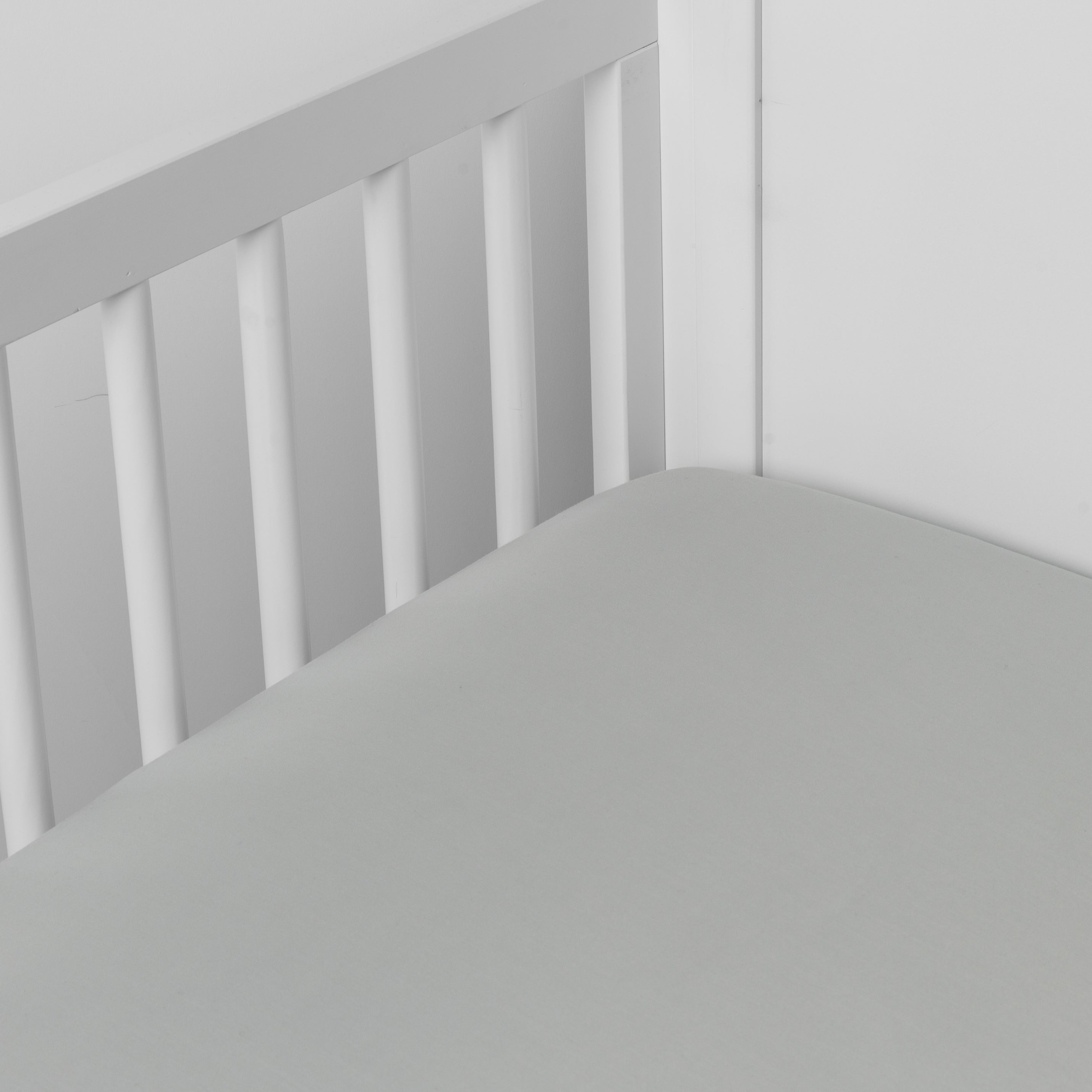 Mineral:  crib sheet shown on a mattress shown from overhead into the corner of a crib. 