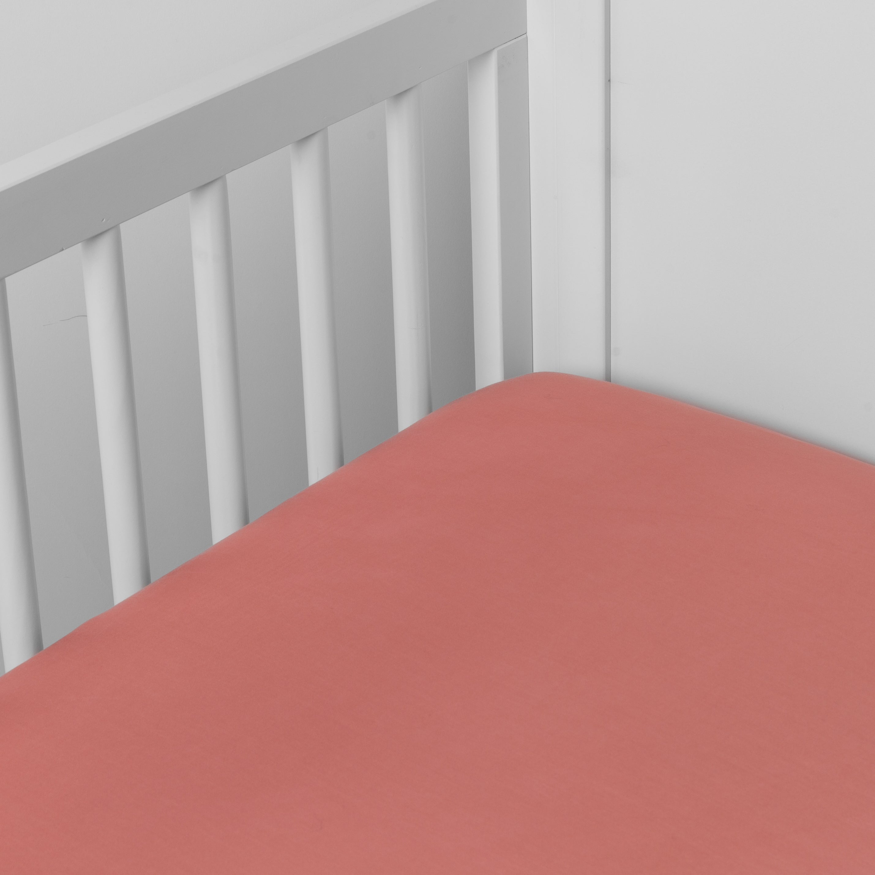 Poppy:  crib sheet shown on a mattress shown from overhead into the corner of a crib. 