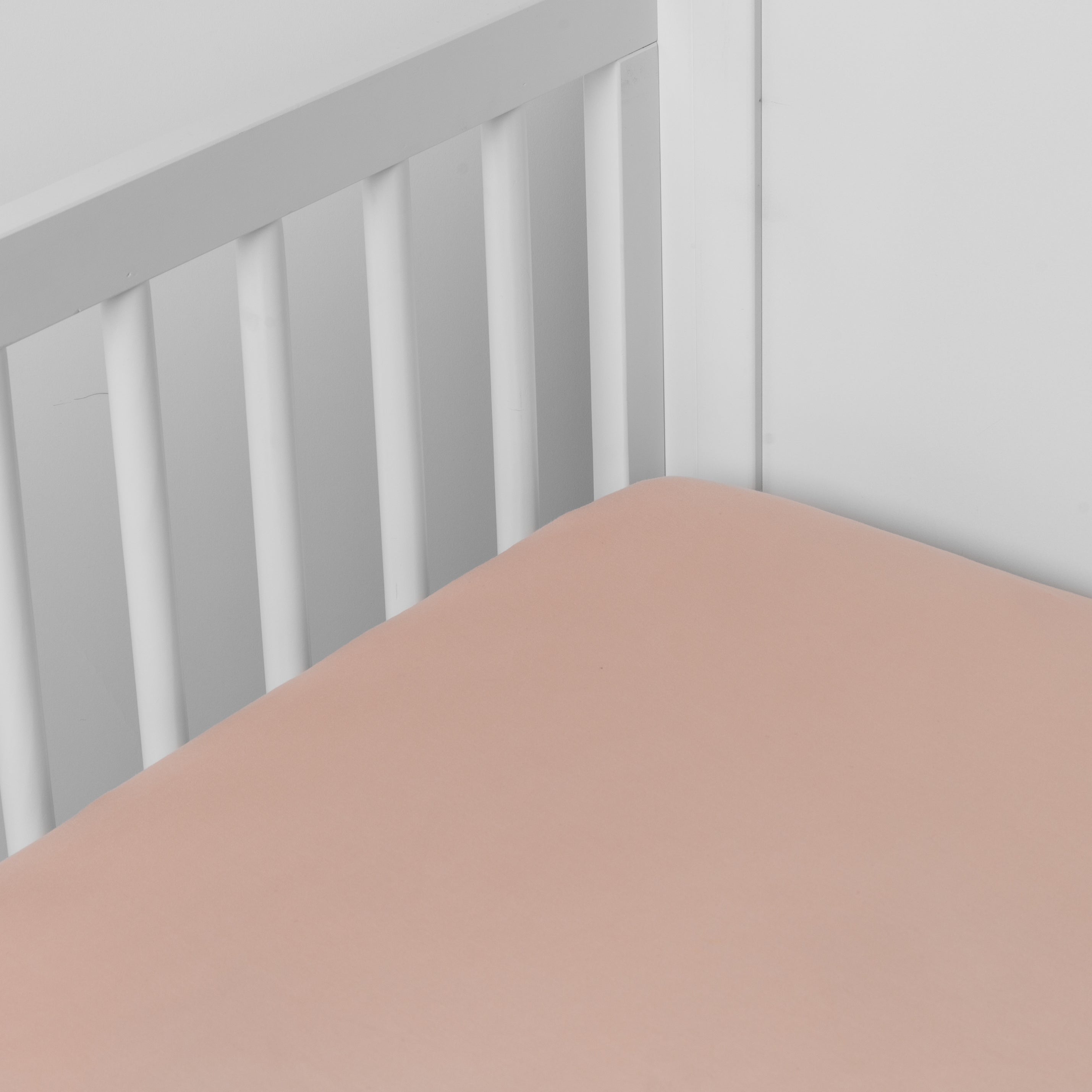 Rouge:   crib sheet shown on a mattress shown from overhead into the corner of a crib. 