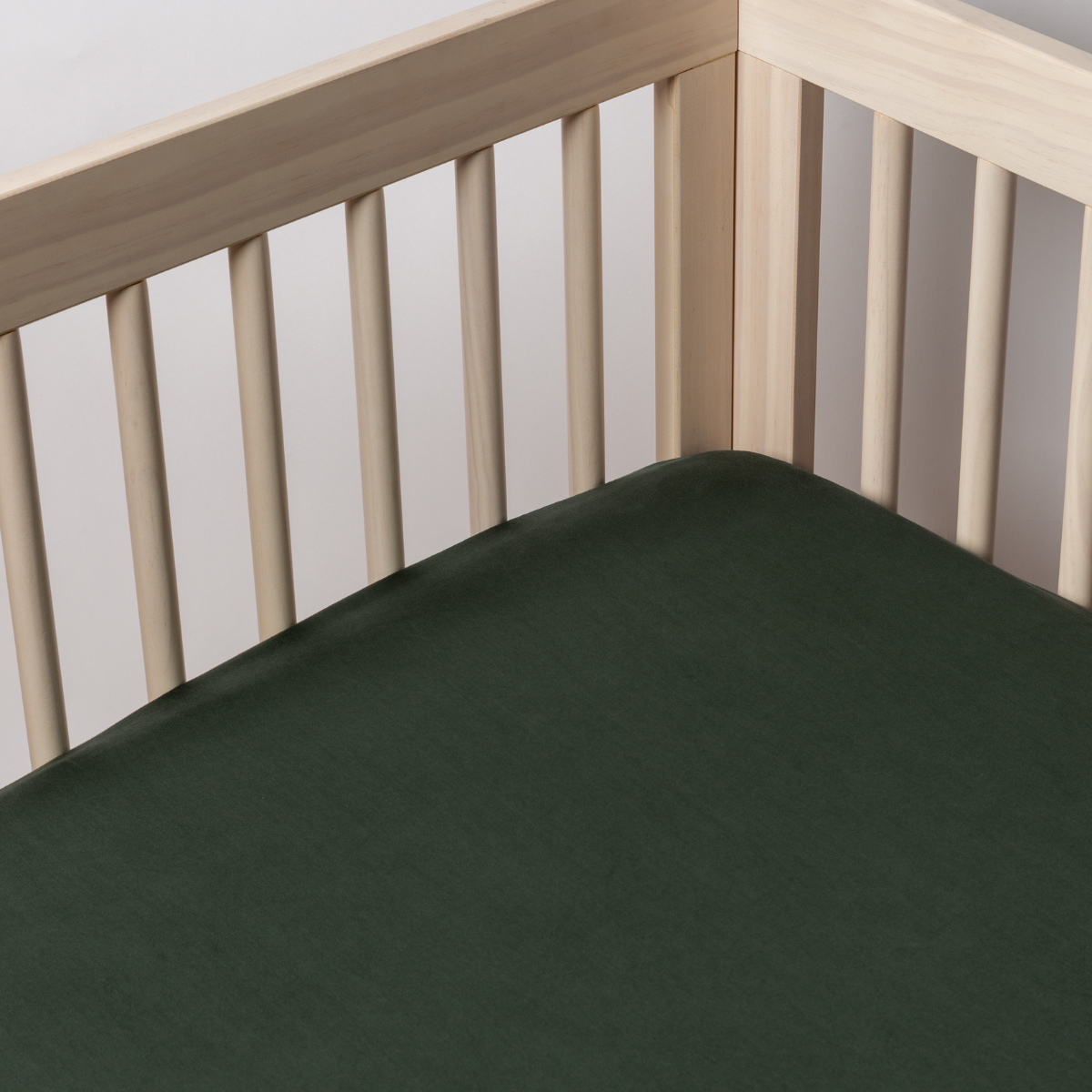 Juniper: a shot of a tencel crib sheet shot into the inside corner of a crib. 