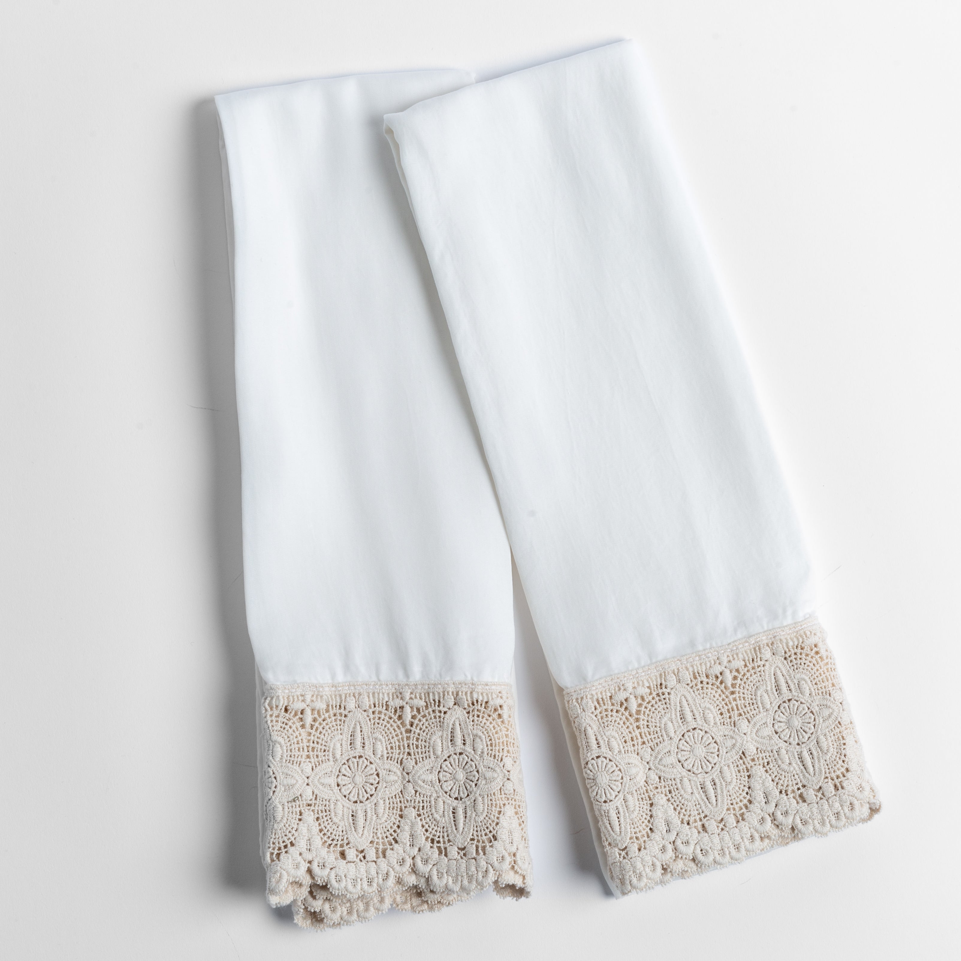 cotton lace trimmed tencel pillowcases folded and shot from overhead against a white background