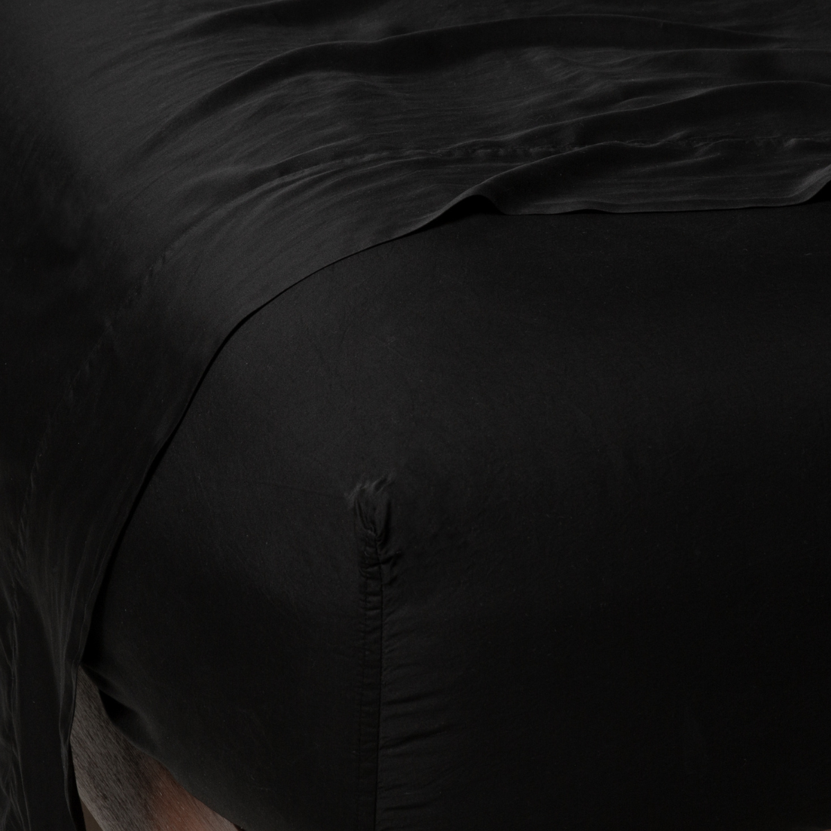 Corvino: fitted sheet with matching rumpled flat sheet - top corner view.