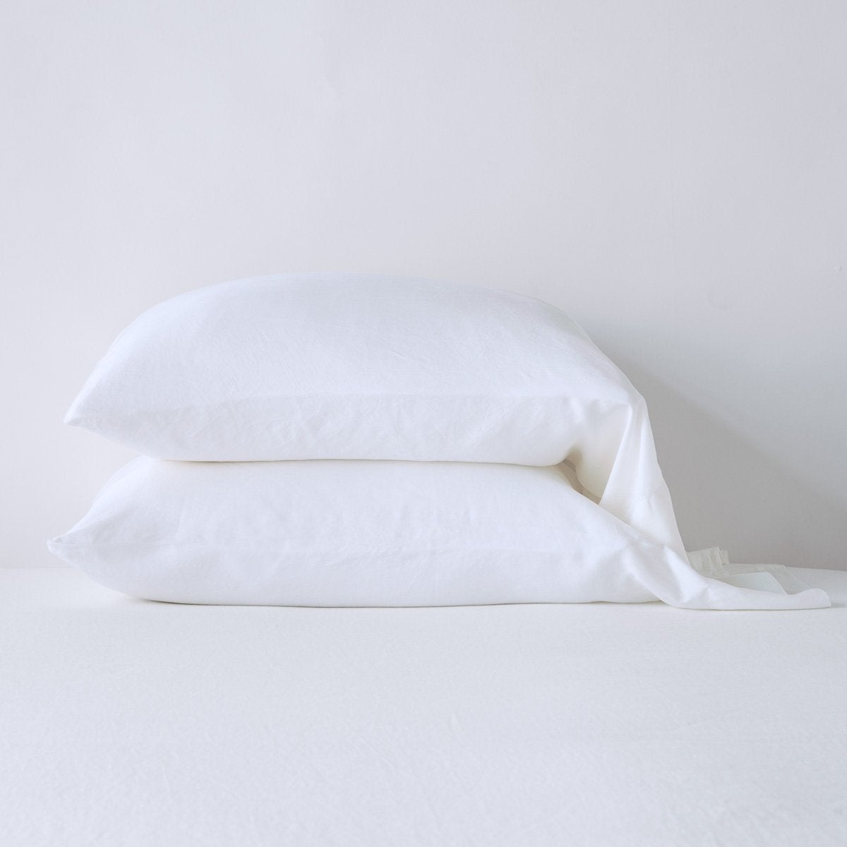White: sleeping pillows stacked neatly against a white backdrop - side view.