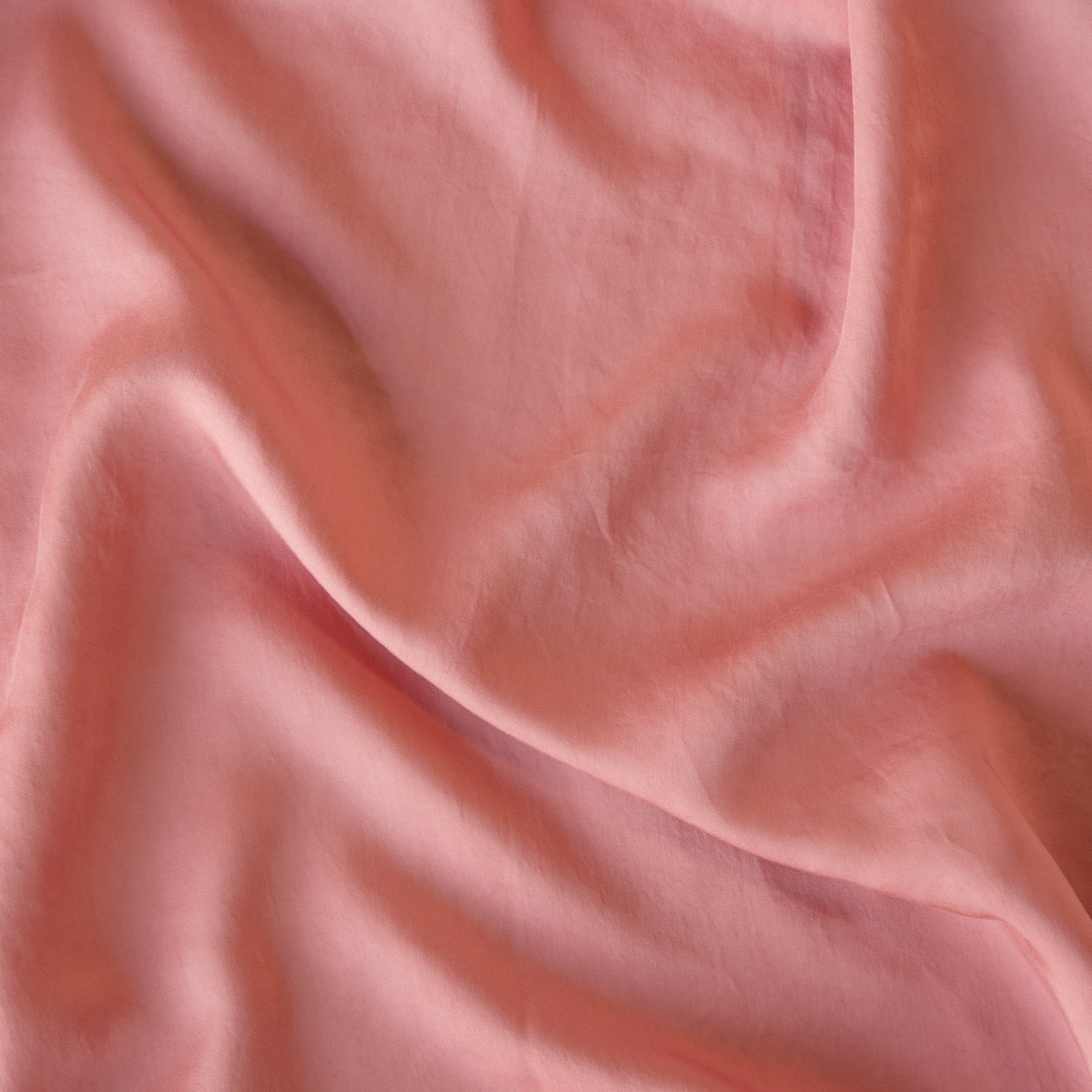 Poppy: A close up of Tencel™ fabric in poppy, a warm coral pink.