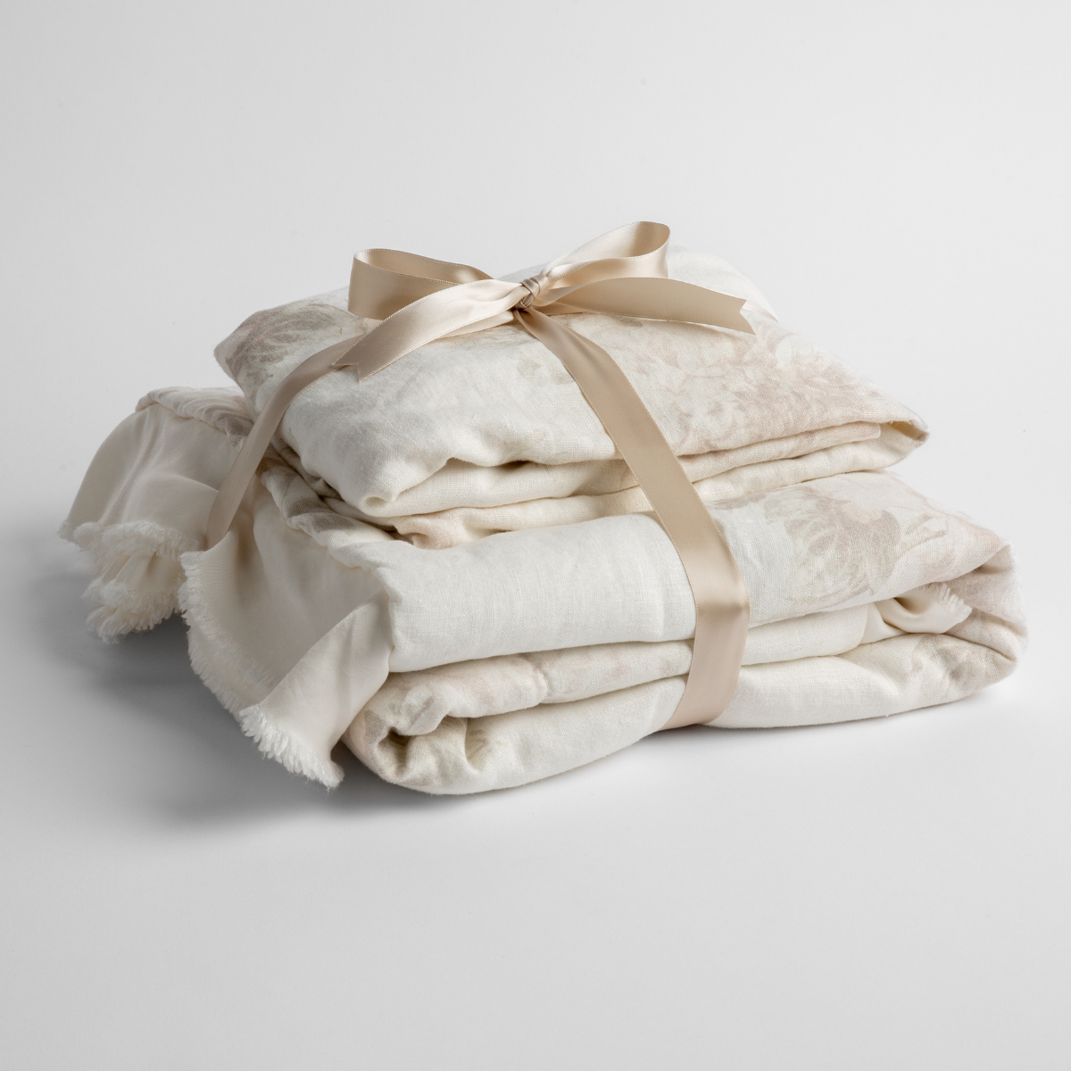 : Matching crib sheet and baby blanket folded and tied with a neutral colored ribbon, shot slightly overhead on a plain white background. 