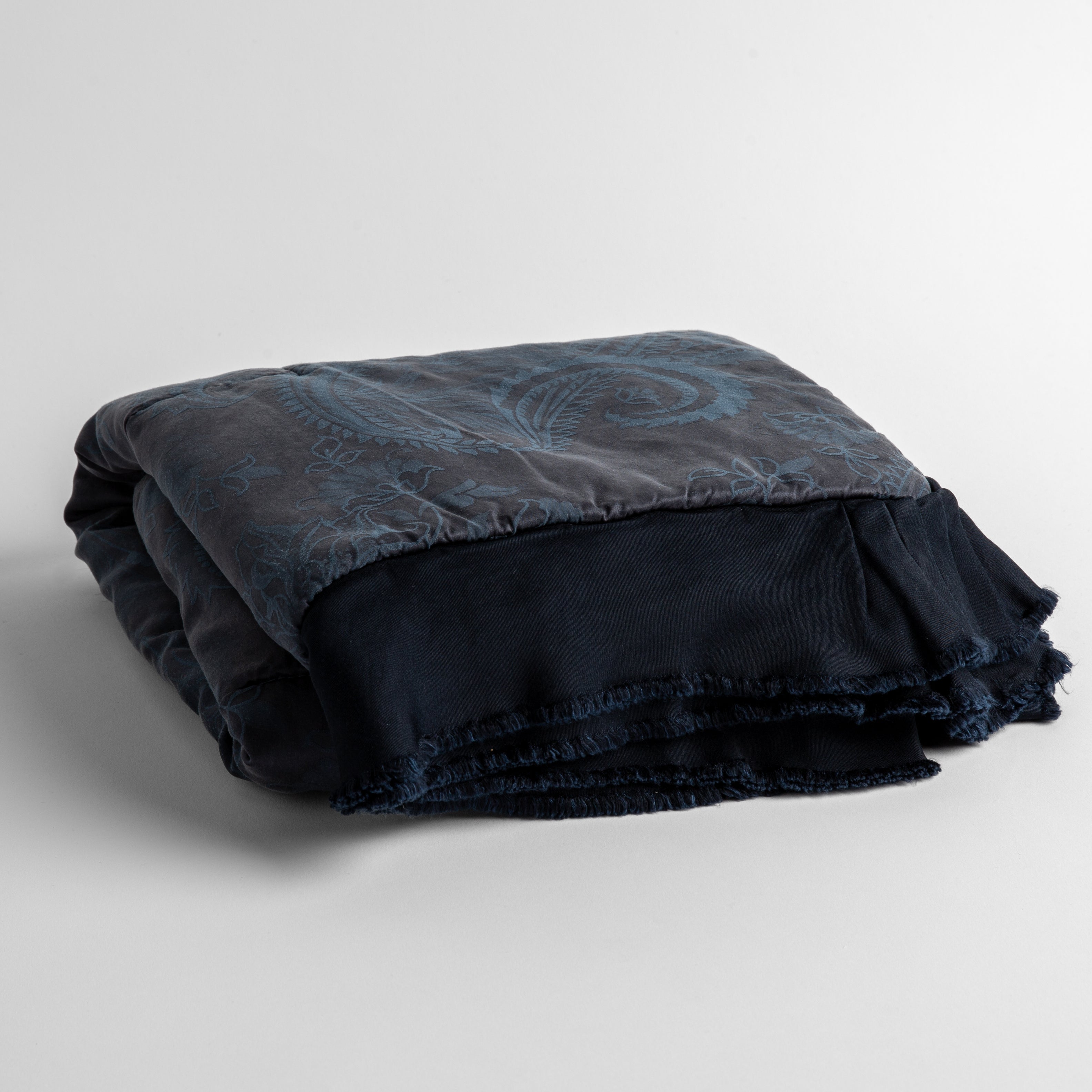 Midnight: silk and tencel™ blend jacquard baby blanket folded and shot from a slight overhead angle to show the trim detail against a white background.