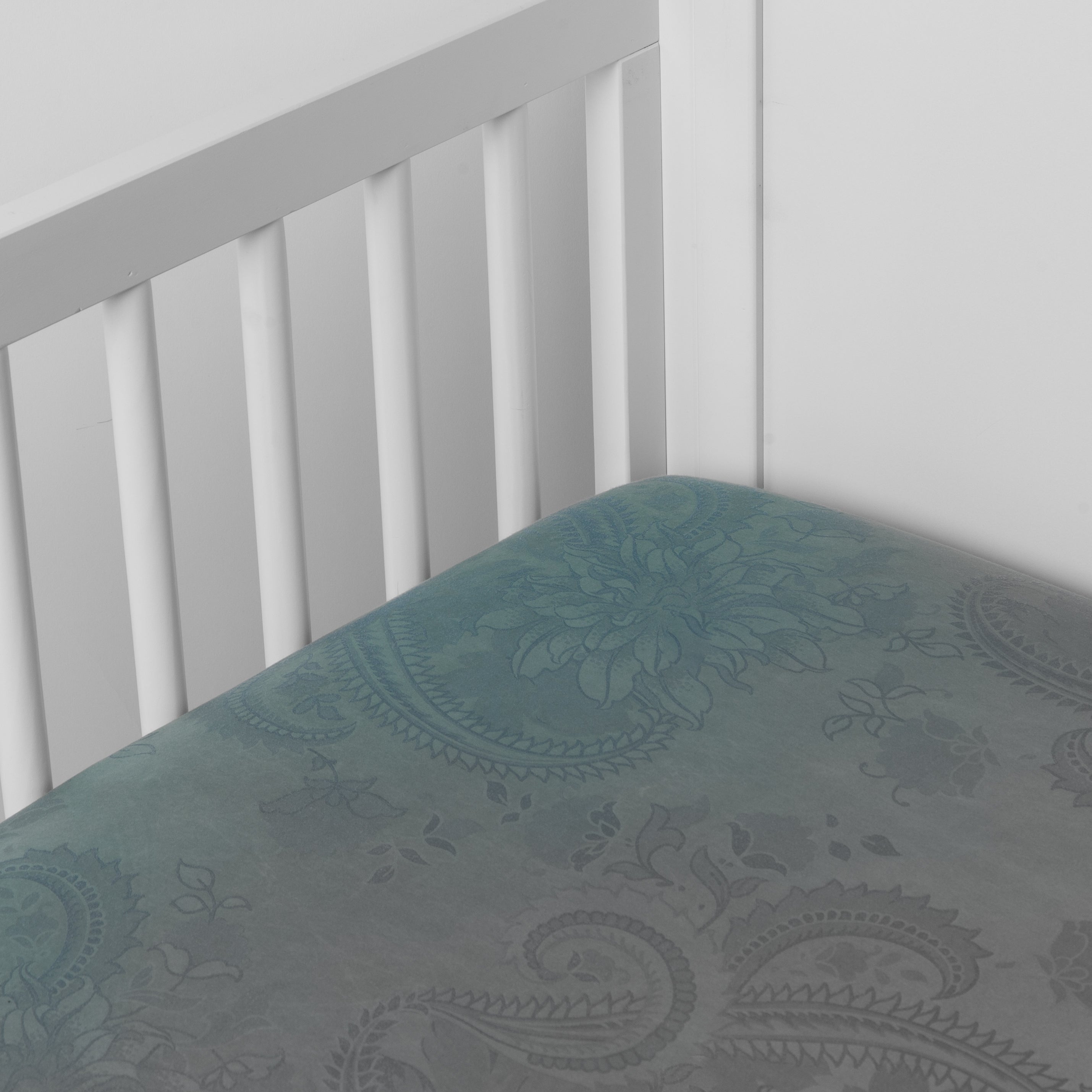 Cenote: a silk and tencel™ crib sheet shown slightly overhread and shot into the corner of a white crib. 