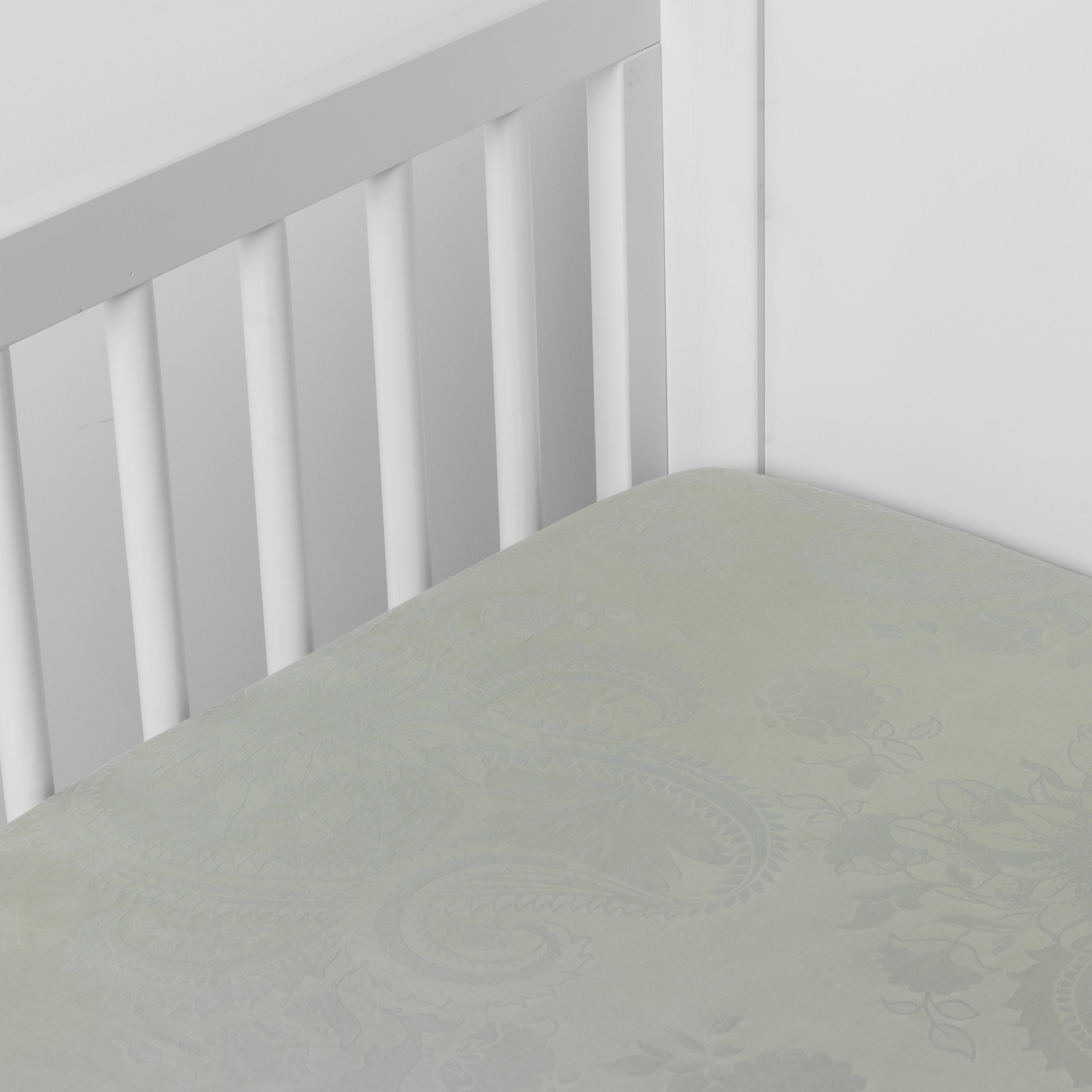 Eucalyptus:  silk and tencel™ blend jacquard crib sheet shot from above at a slight angle into the corner of a white crib. 